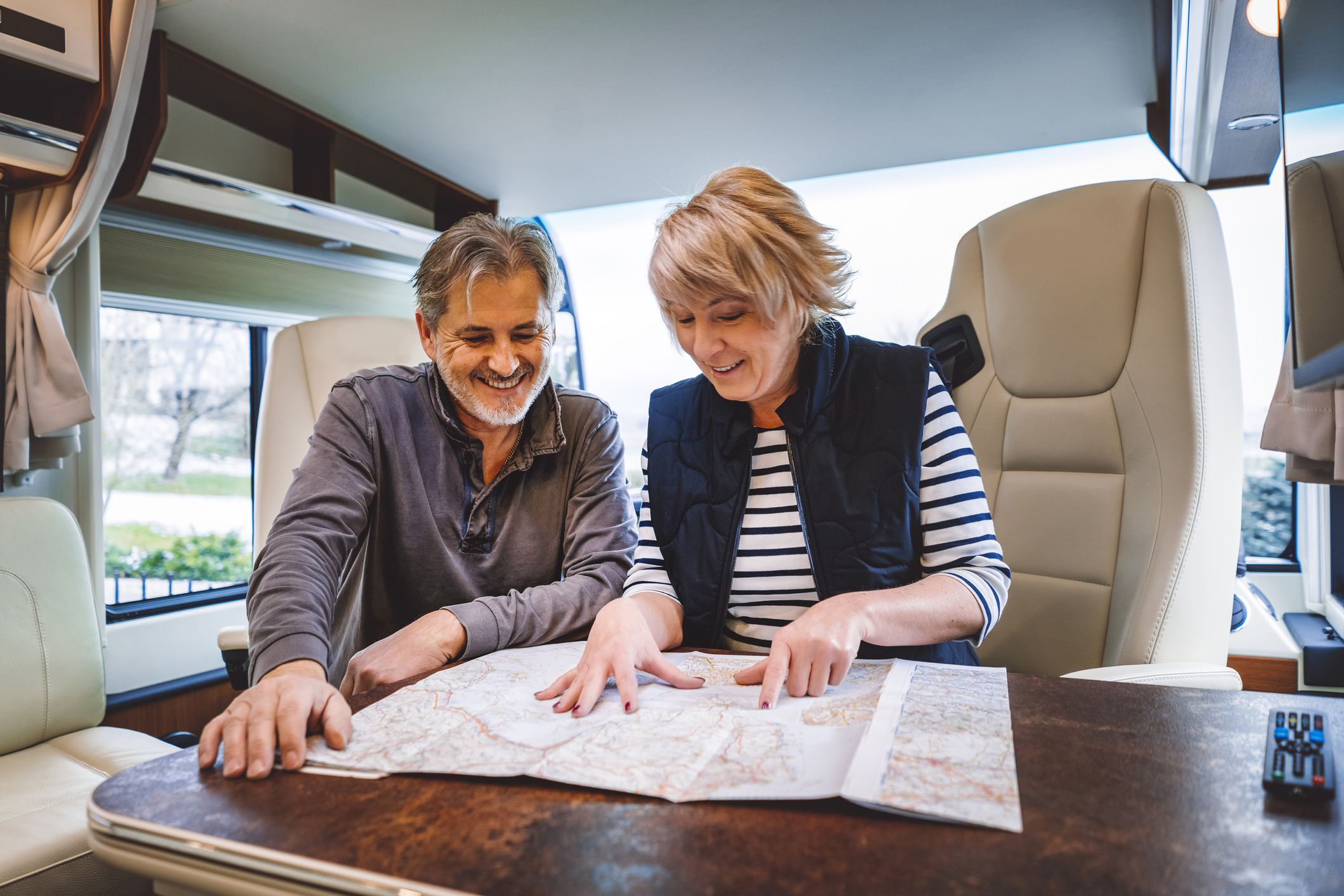 smiling couple looking at map on table in rv