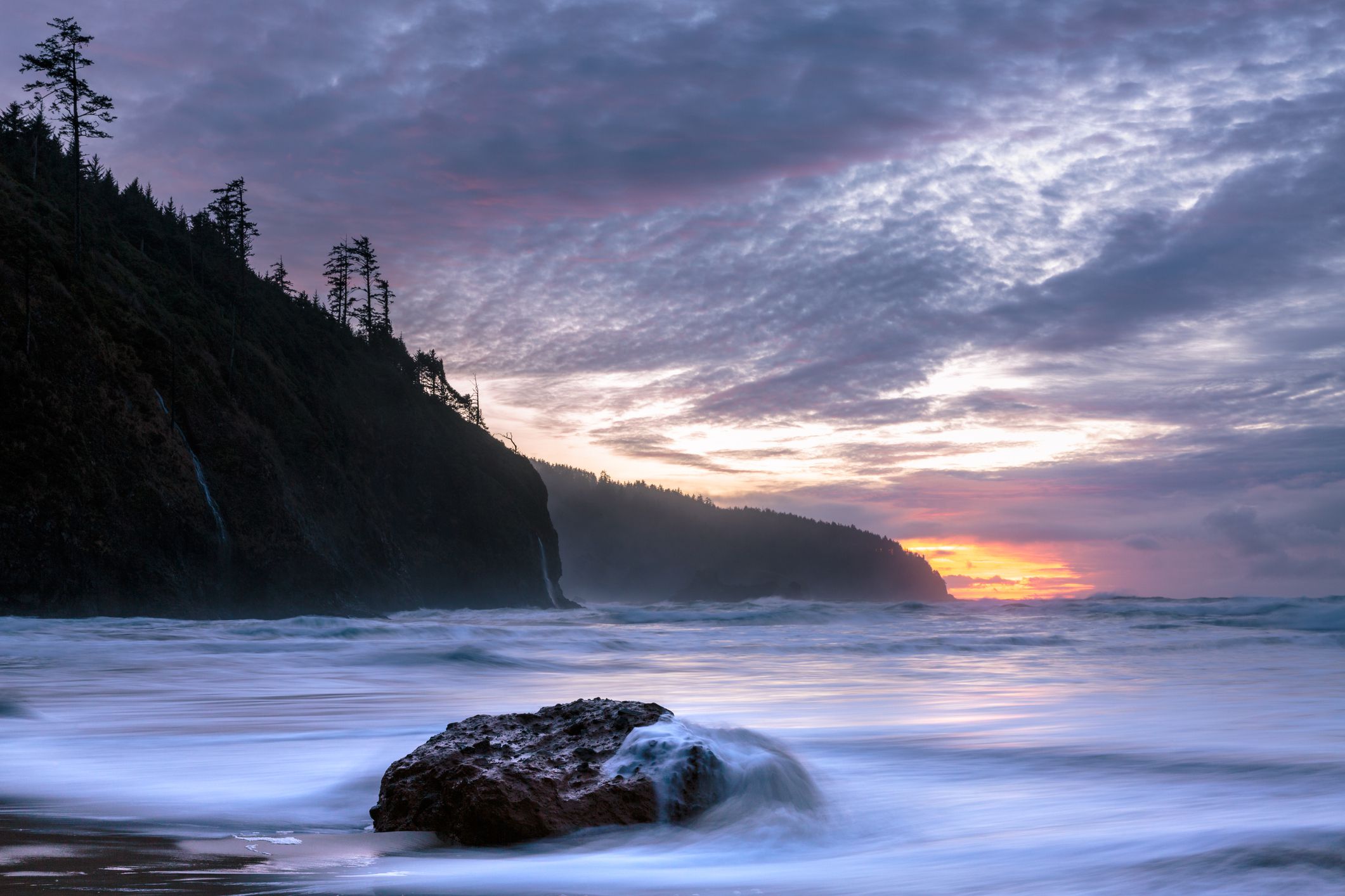 Long exposure of a wave rushing over a rock at sunset, Cape Lookout State Park, Oregon