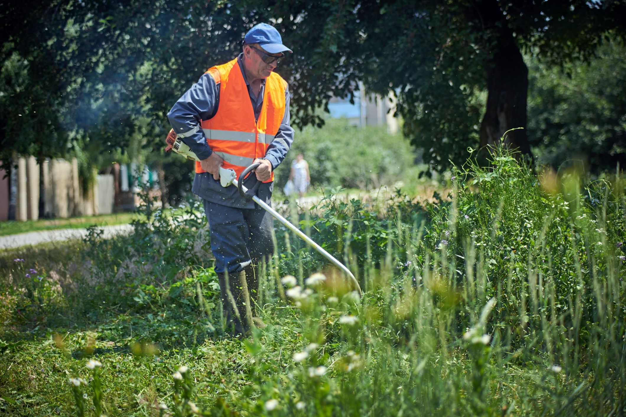 man trims grass in uniform