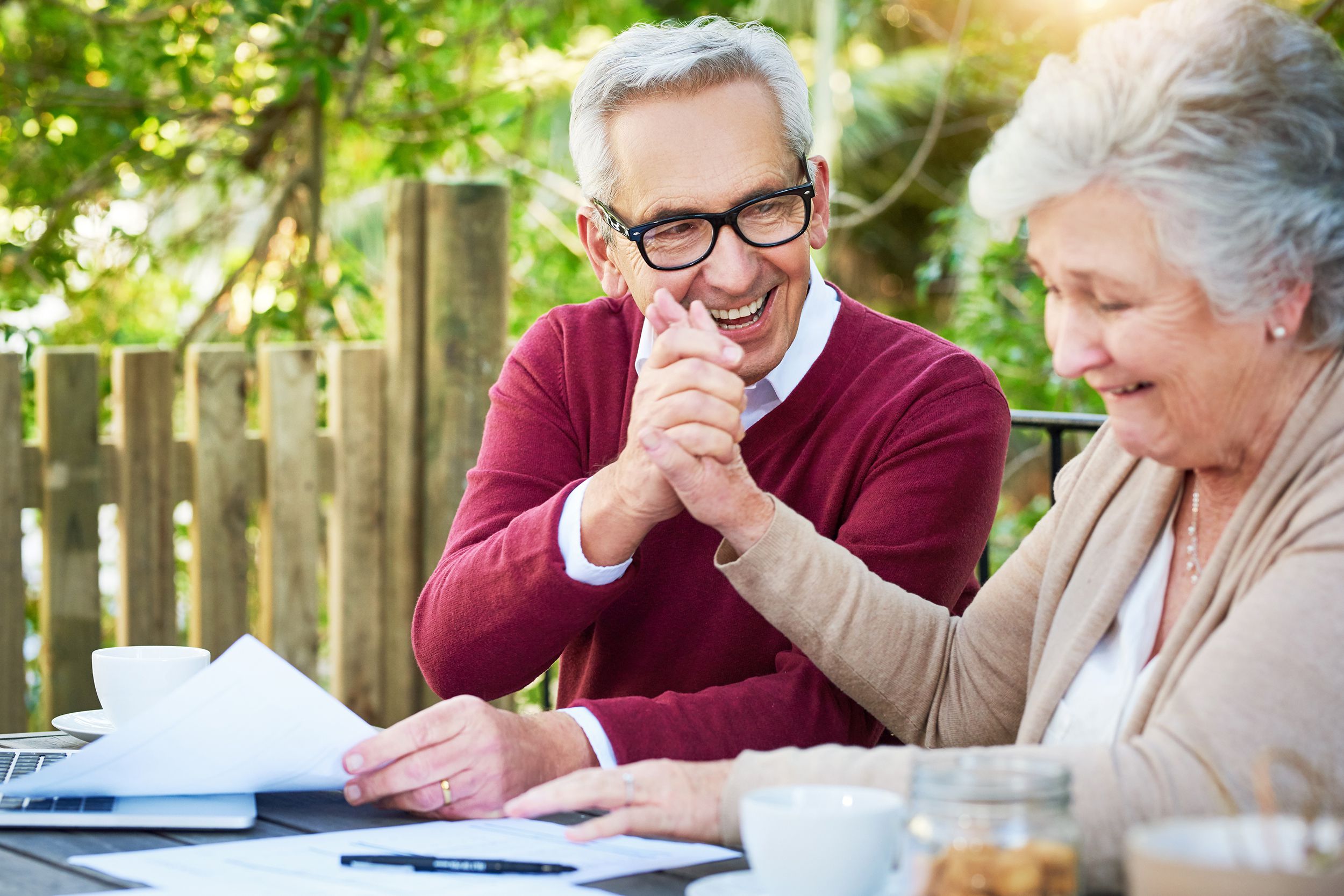 senior couple doing taxes outside, woman giving high five to man