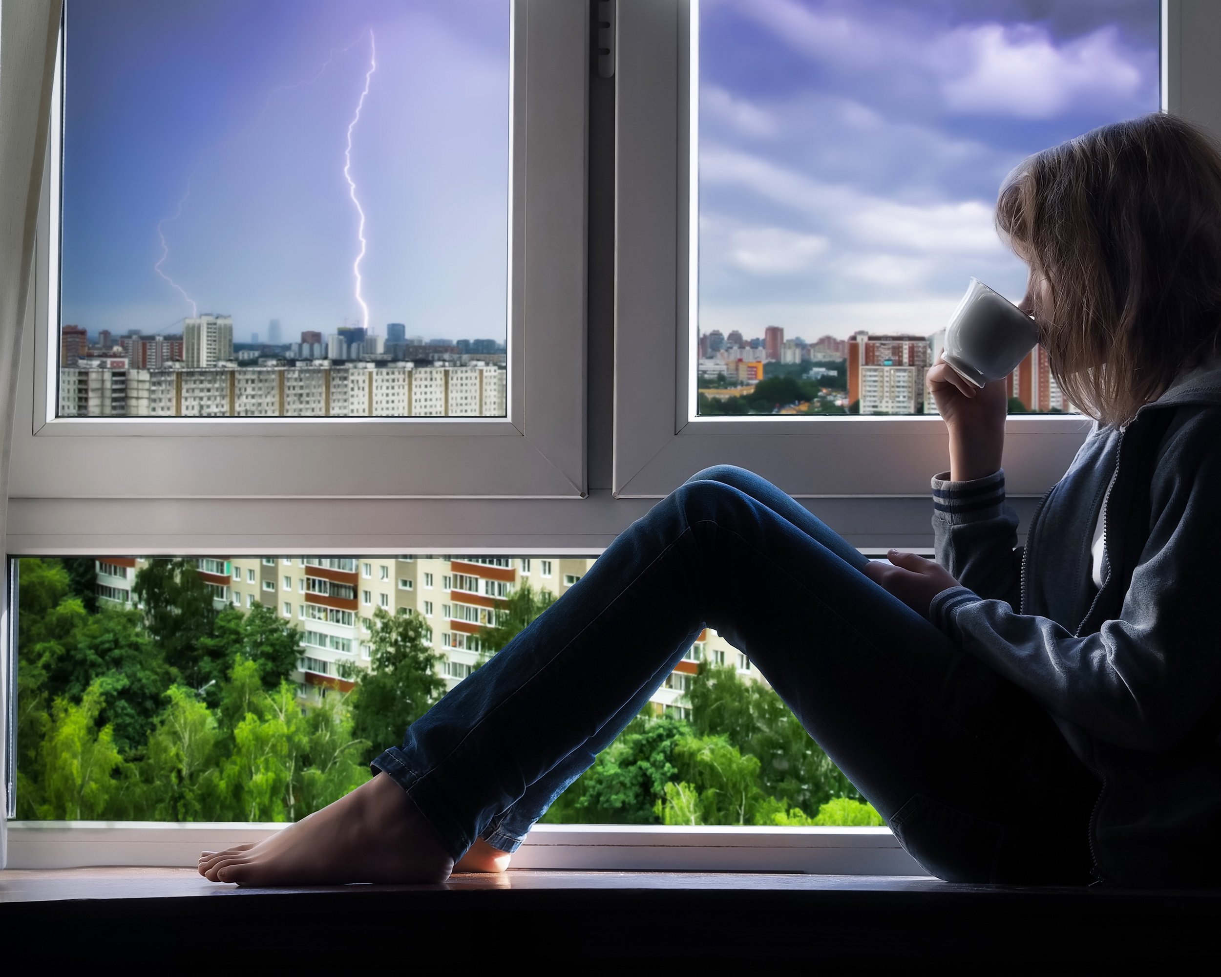 girl watching thunderstorm from window of her apartment