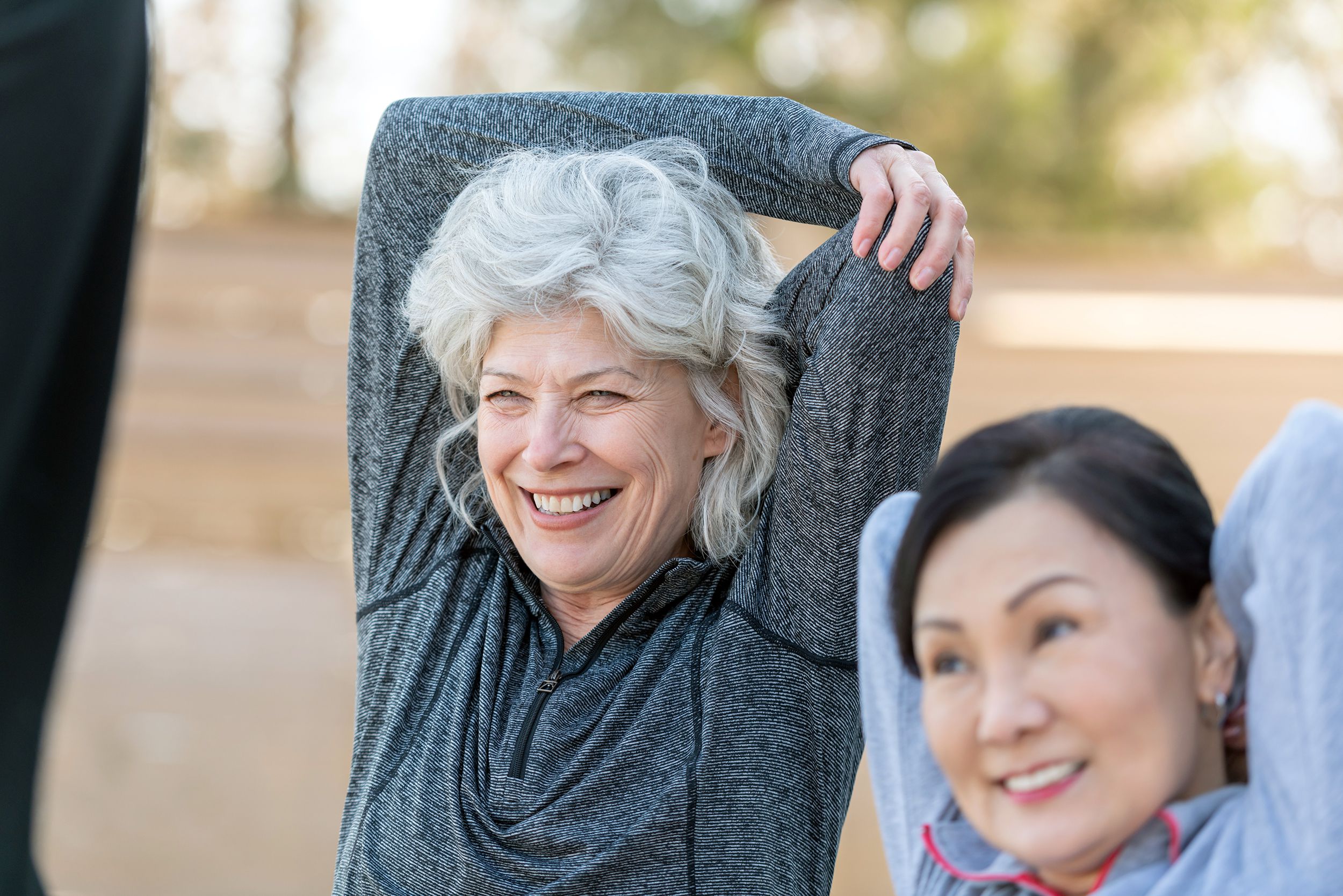 youthful seniors doing stretching in outside exercise class