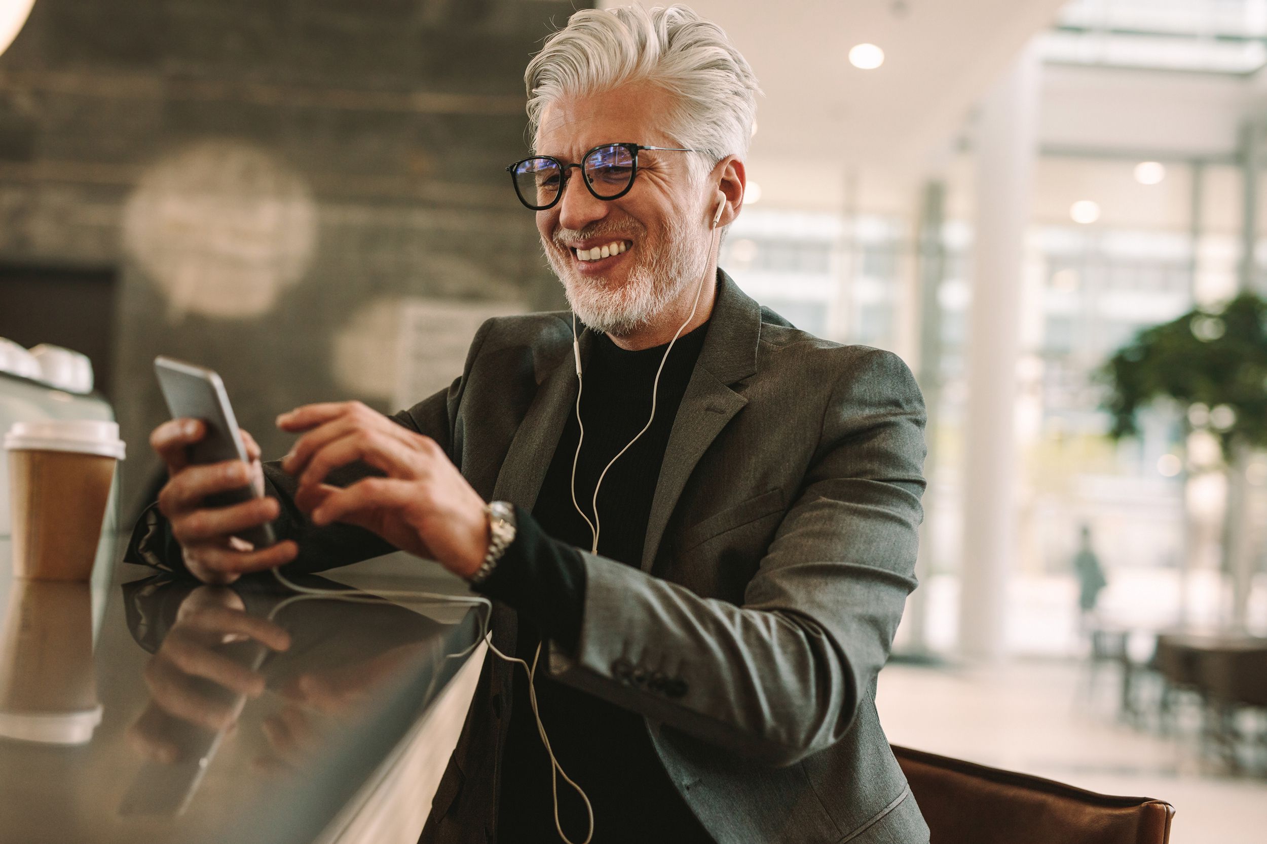 mature businessman using phone at cafe