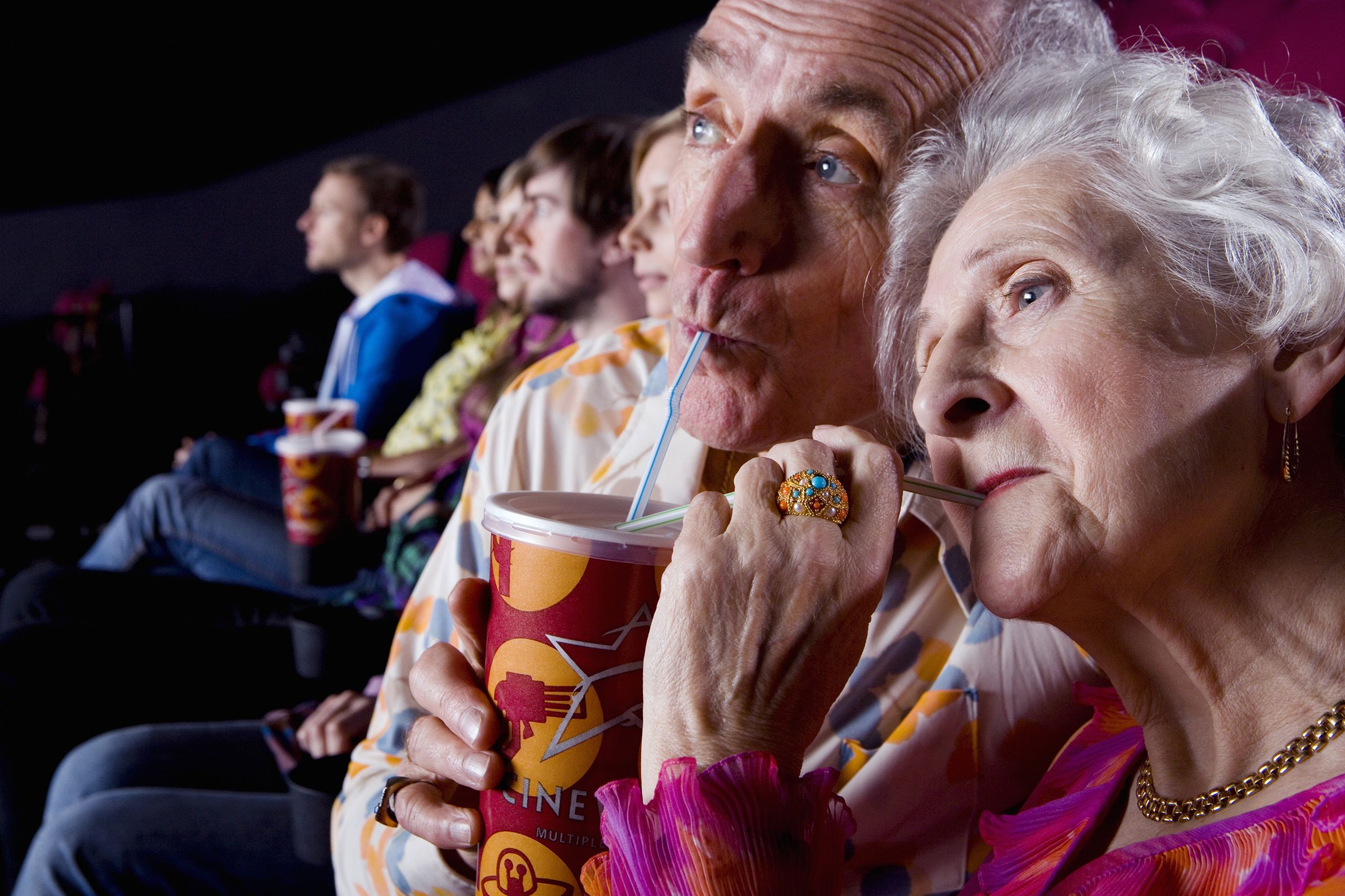 close-up of senior couple sharing drink in cinema