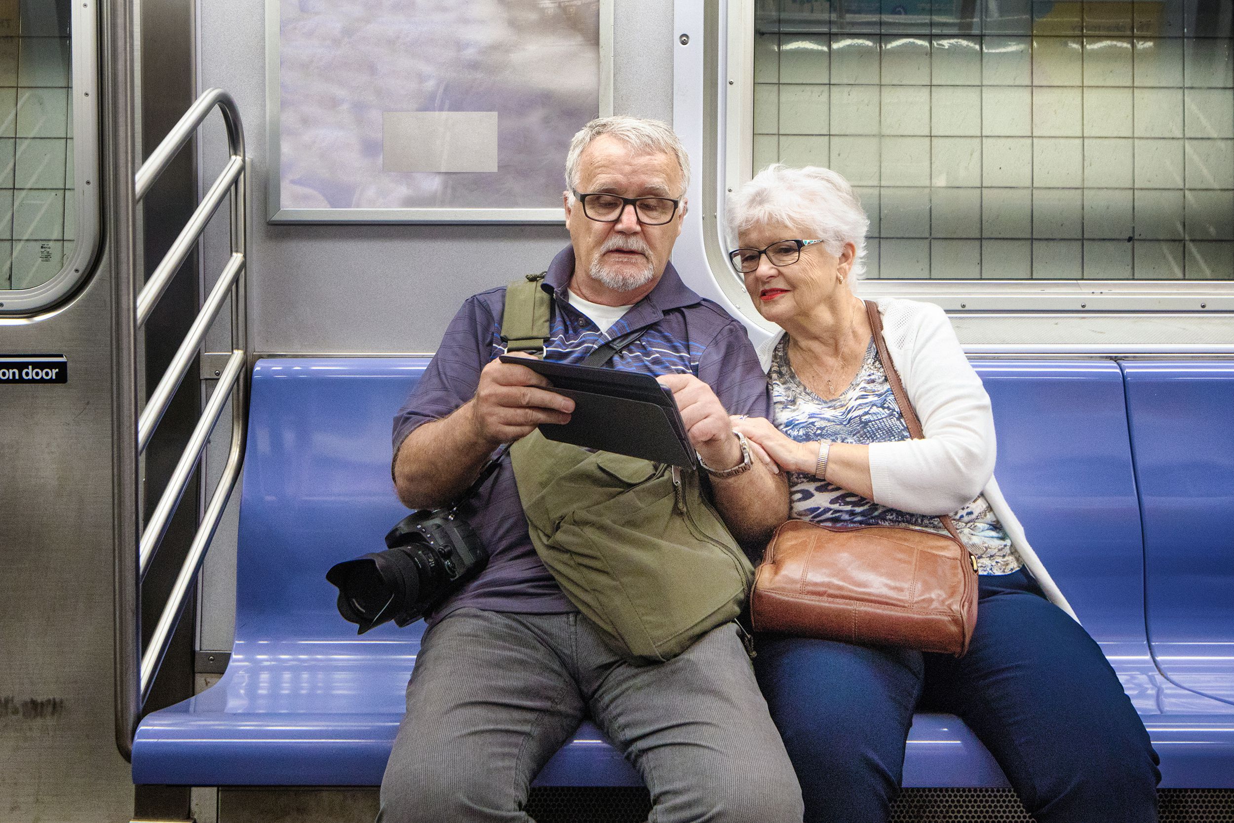 senior couple look at information on tablet while in NYC transit in subway