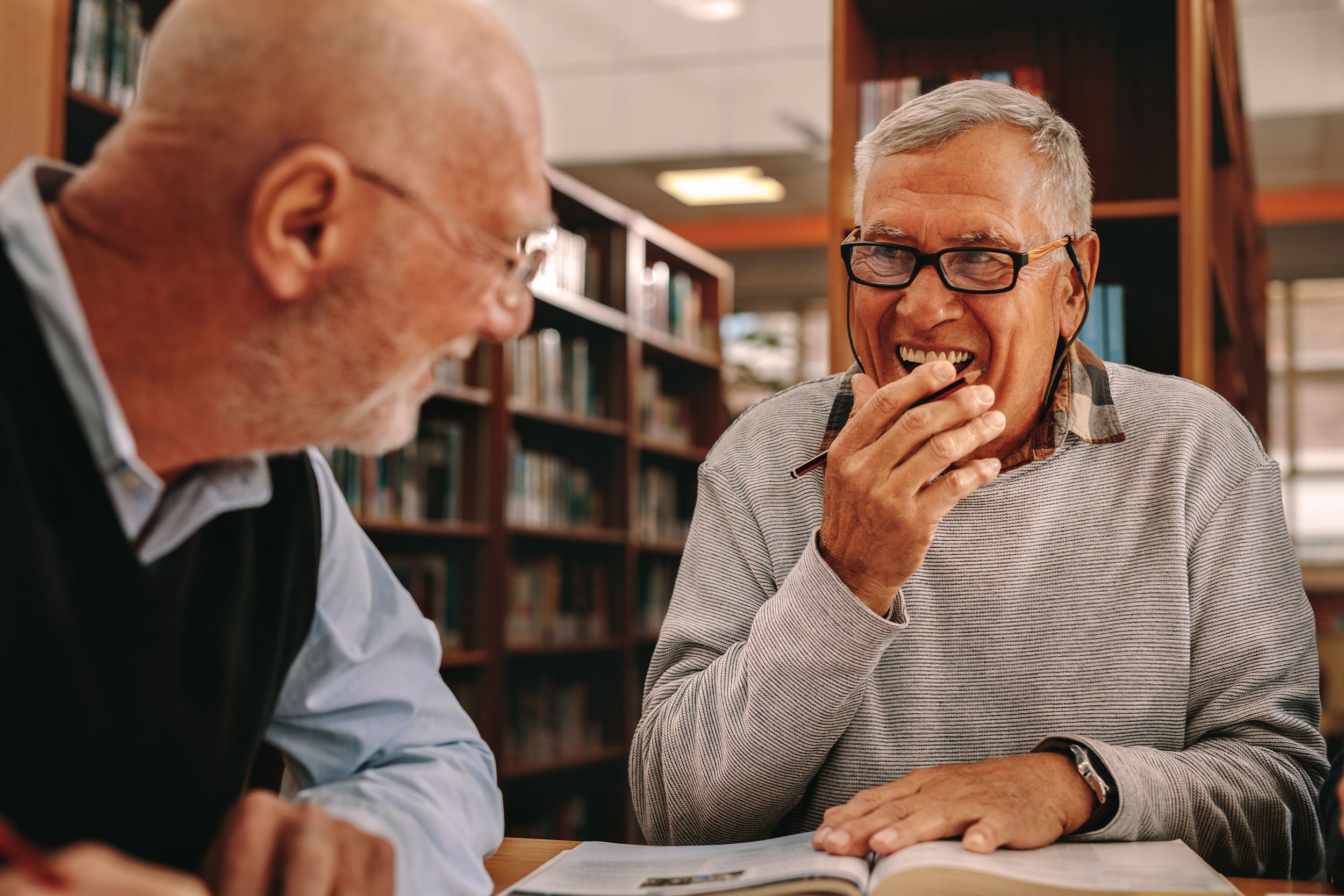senior men sitting in a library and studying