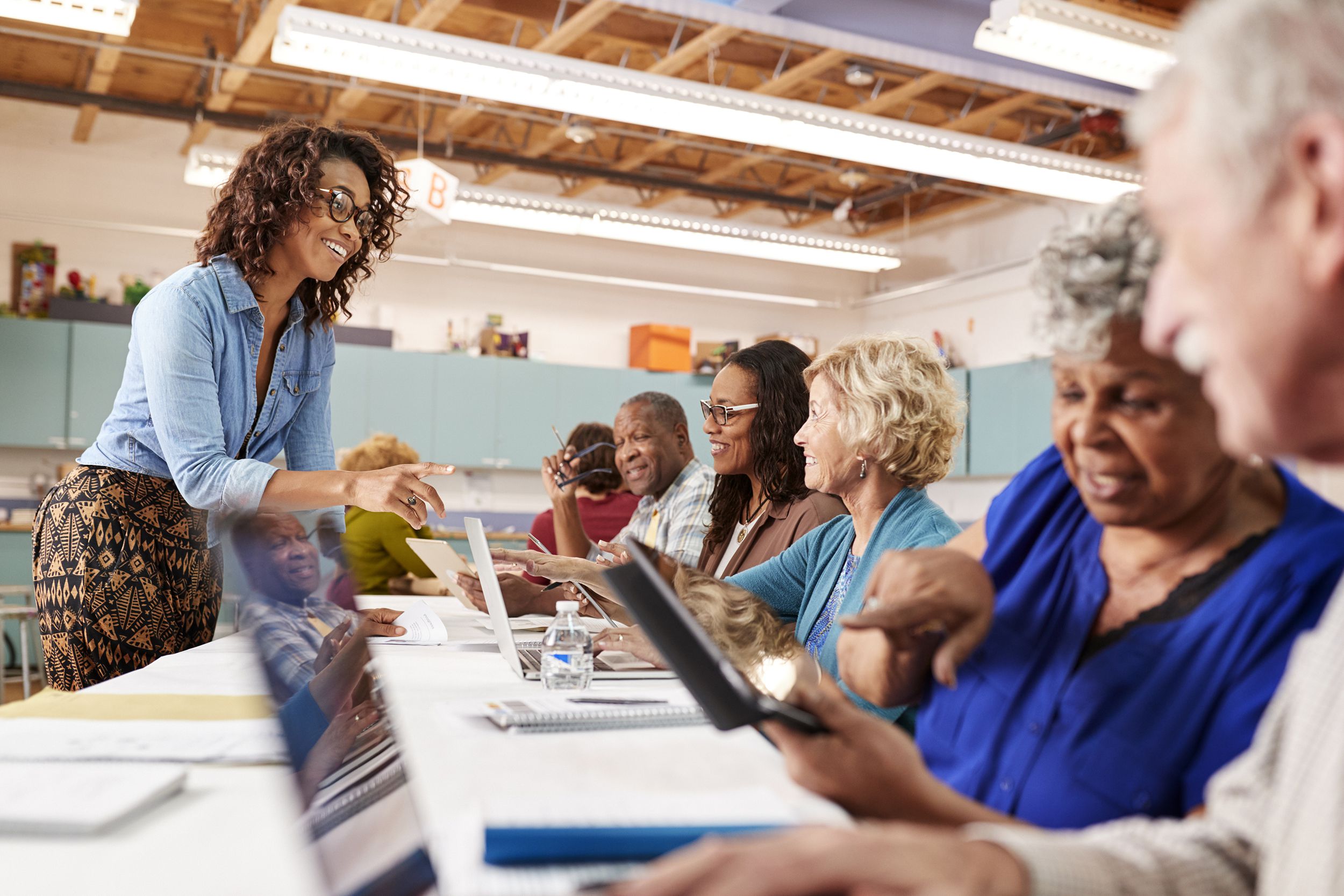 group of retired seniors attending it class in community centre with teacher