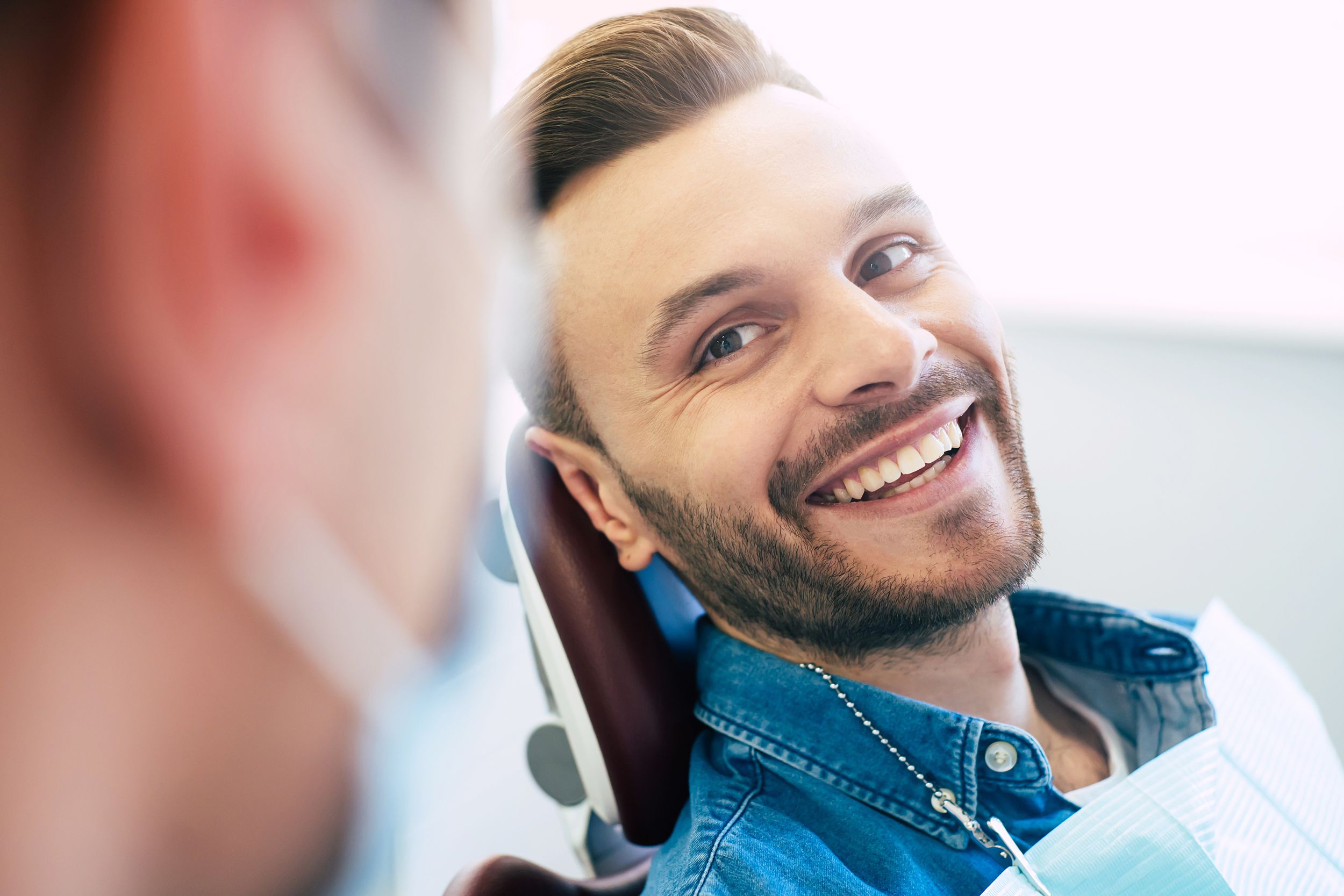 patient in chair at dentist office, talking with dentist
