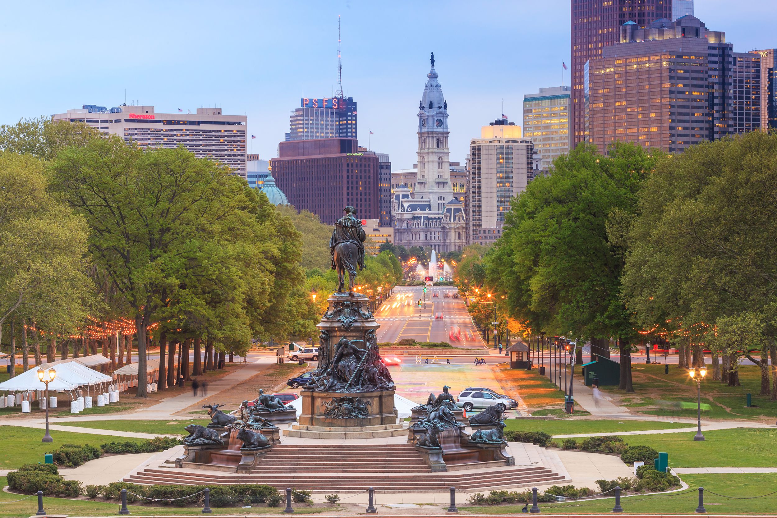 Downtown Philadelphia, trees line the street, Washington Monument in the foreground, large buildings and skyscrapers in the background