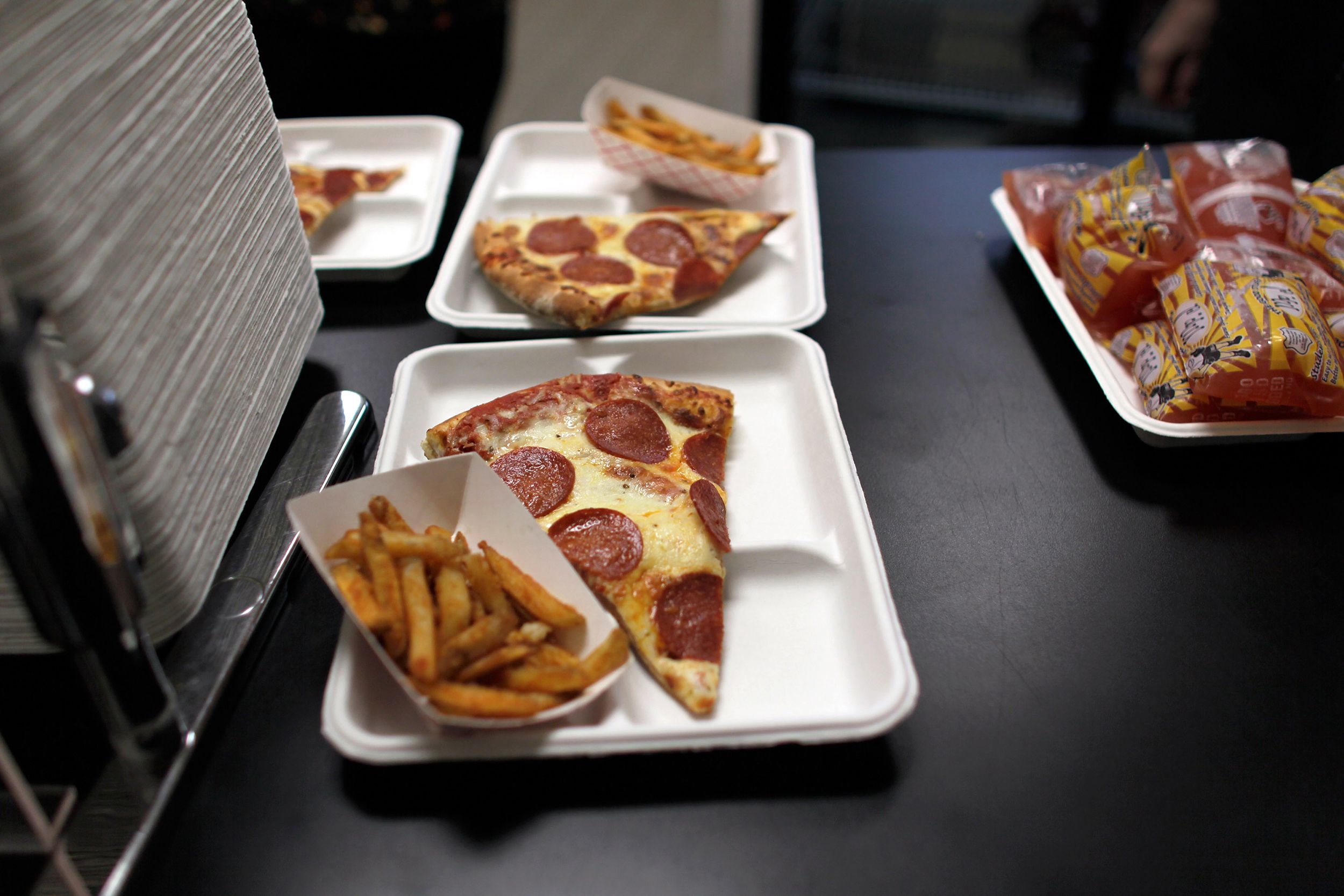 pizza and fries on school lunch tray