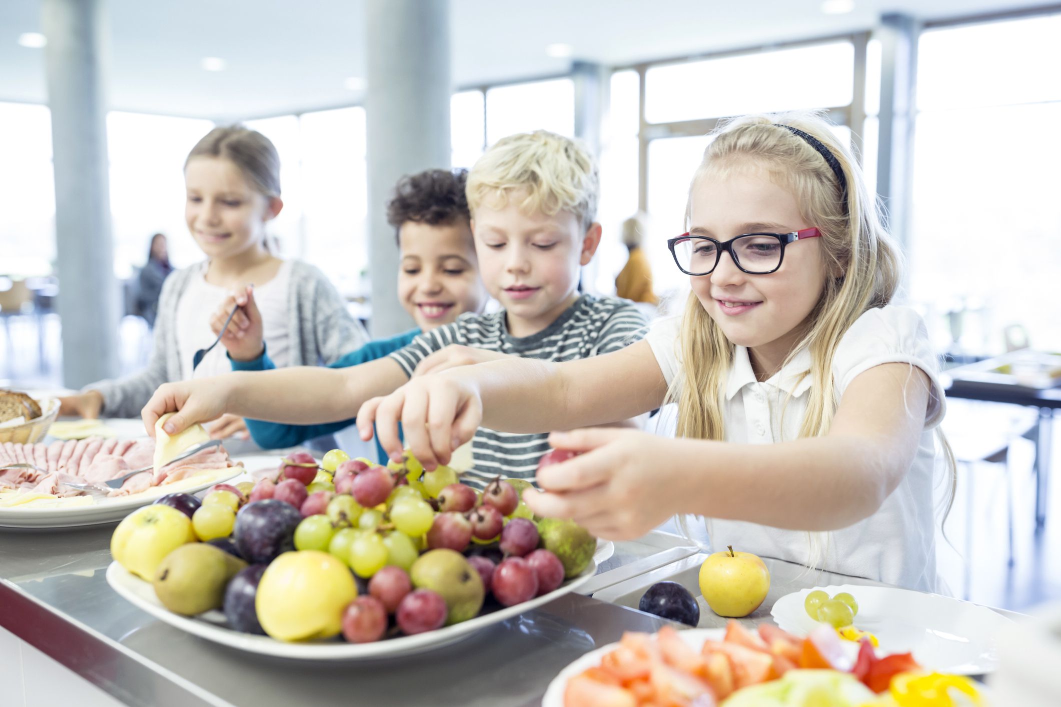 pupils at counter in school canteen germany, with plenty of fresh fruit and vegetables