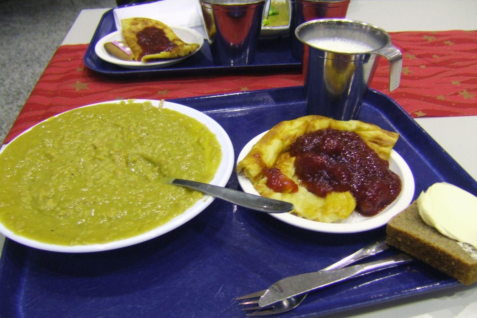 Finnish pea soup with fruit pastry, milk, bread and butter on tray on table