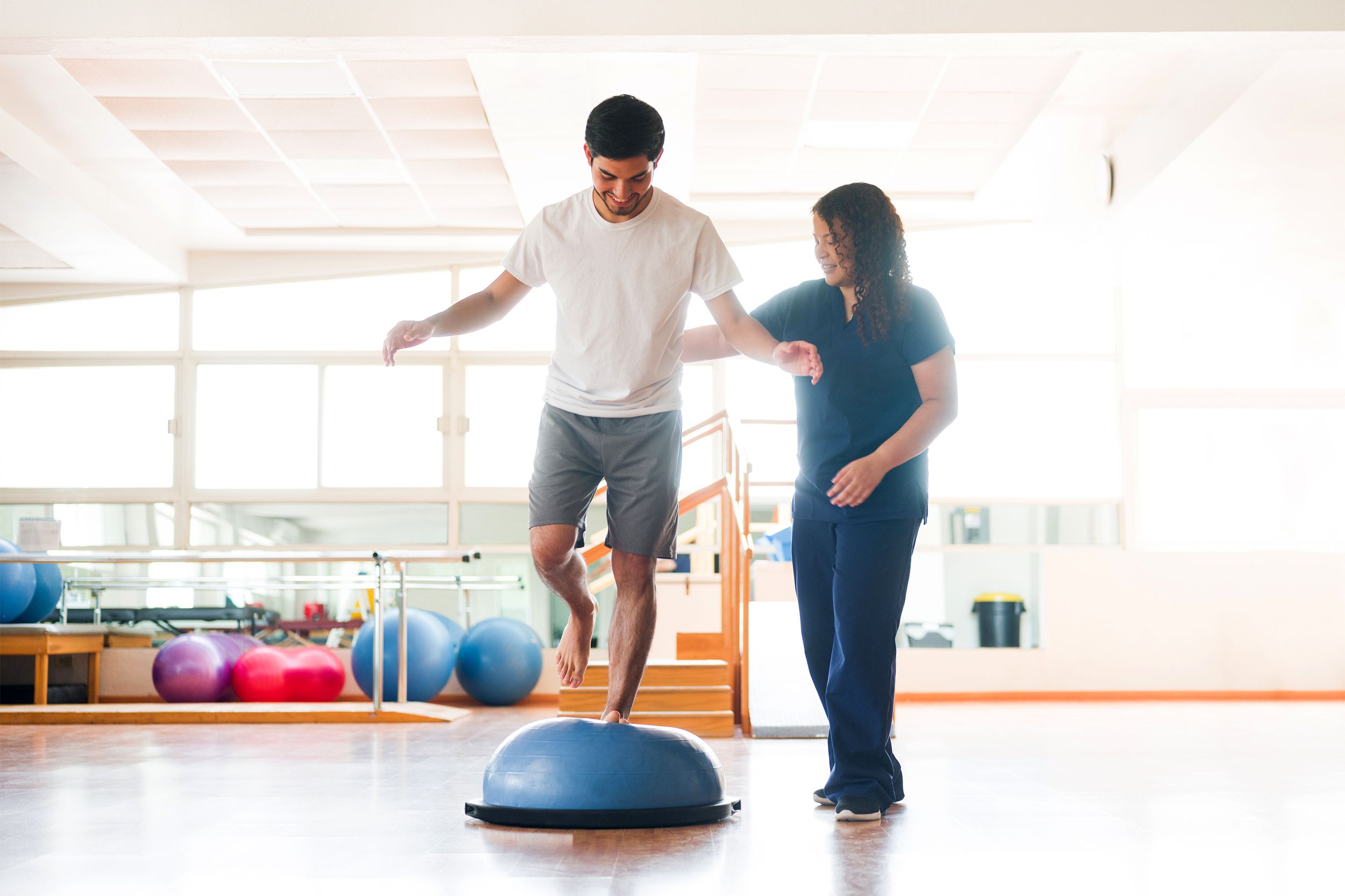 Male physical rehab patient standing on bosu ball