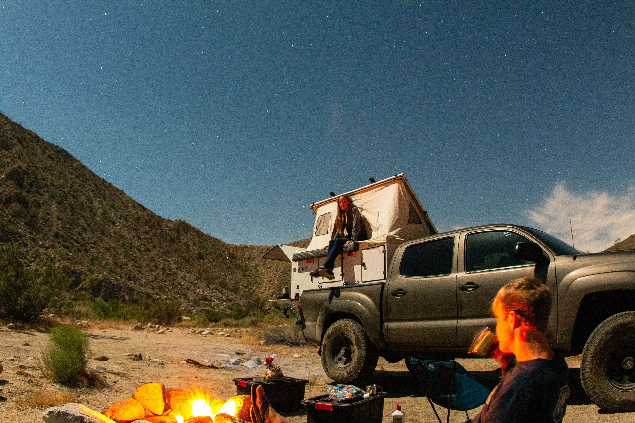 Couple camping at night with a truck camper