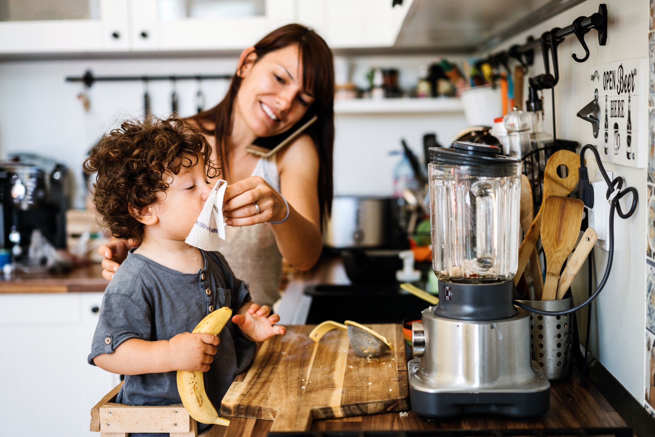 busy mother helping son in kitchen making a phone call