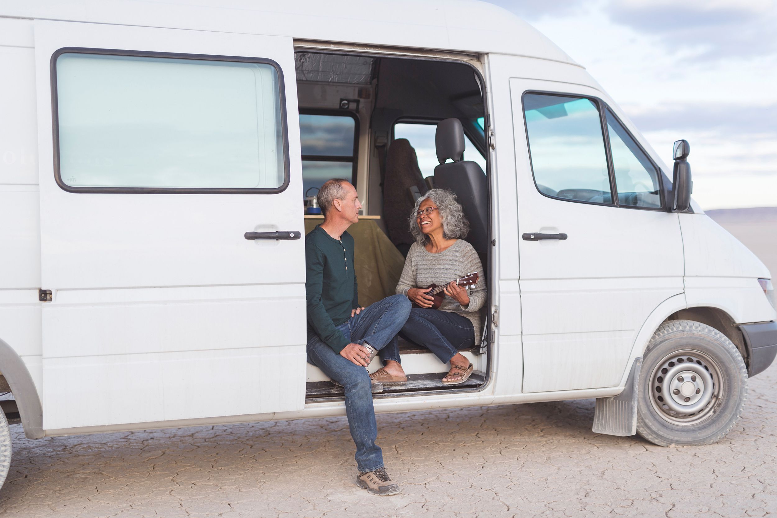 senior couple sitting in their camping van in the desert