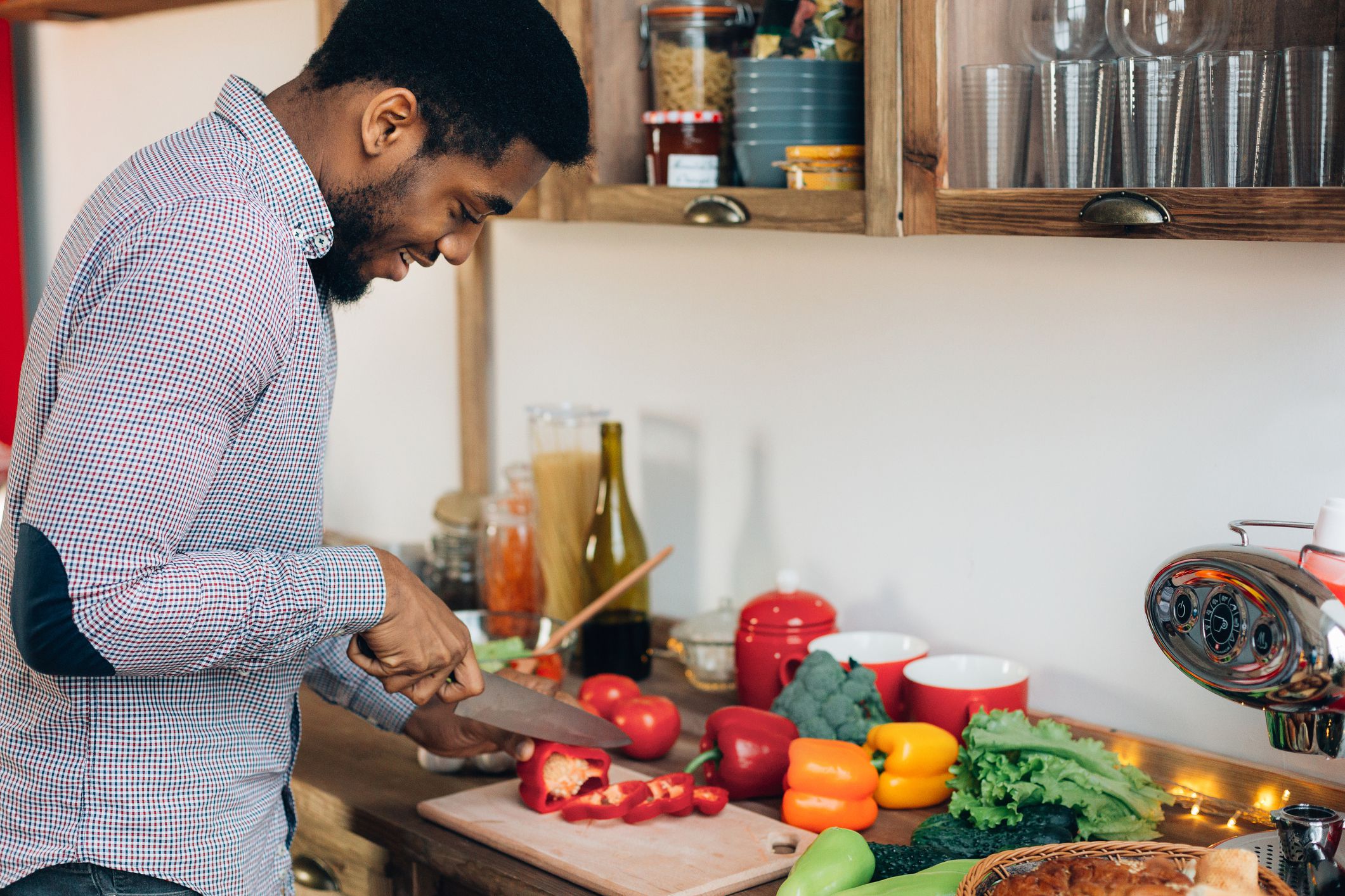 man cuts up peppers on chopping board in kitchen