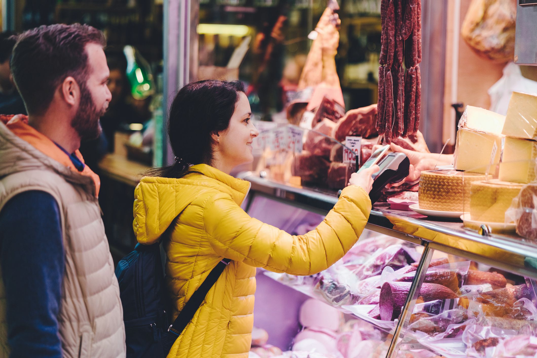 couple buying foreign meat and cheese at supermarket