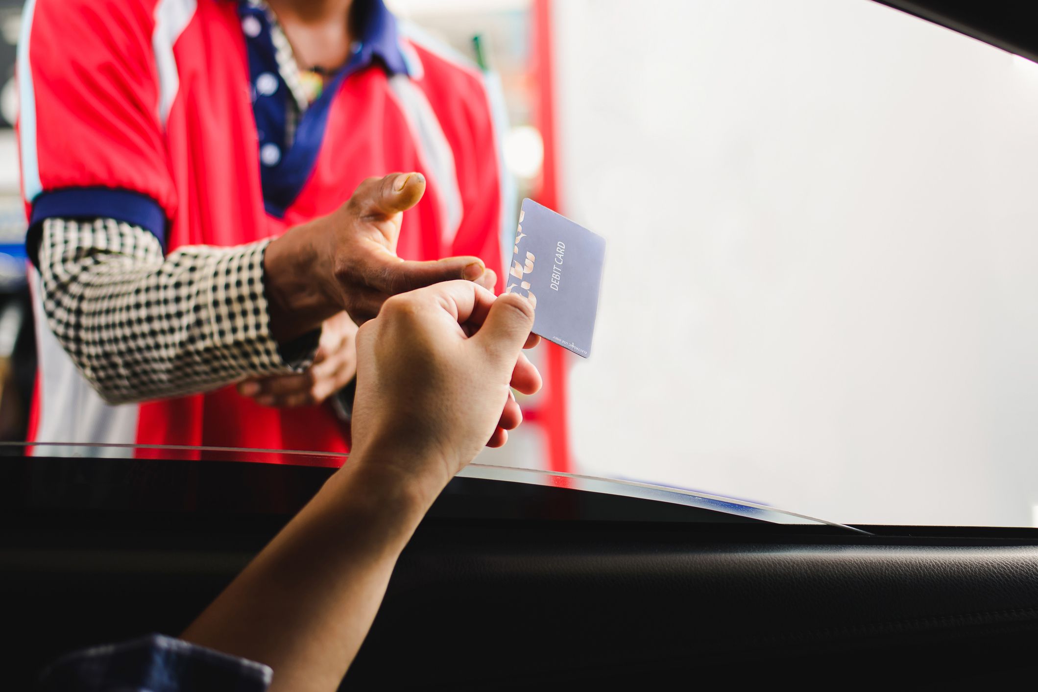arm reaching out car window handing debit card to employee standing outside car