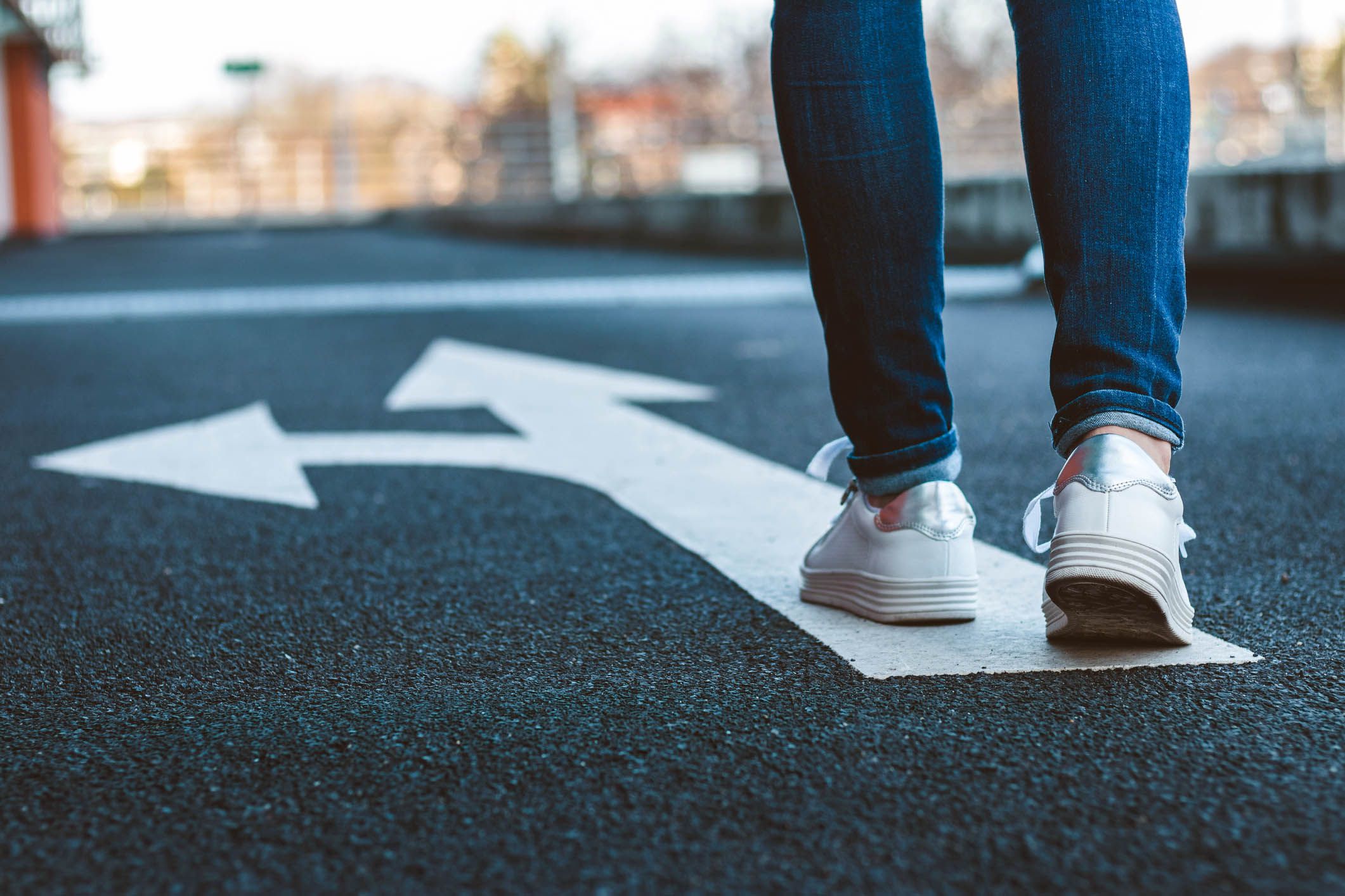 feet walking on directional sign on asphalt road