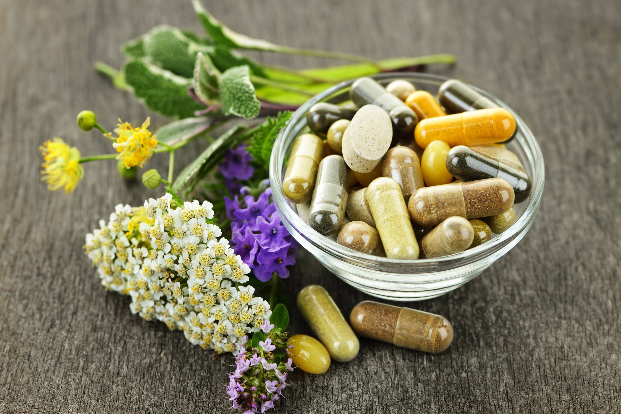 all-natural supplements in bowl with flowers next to it