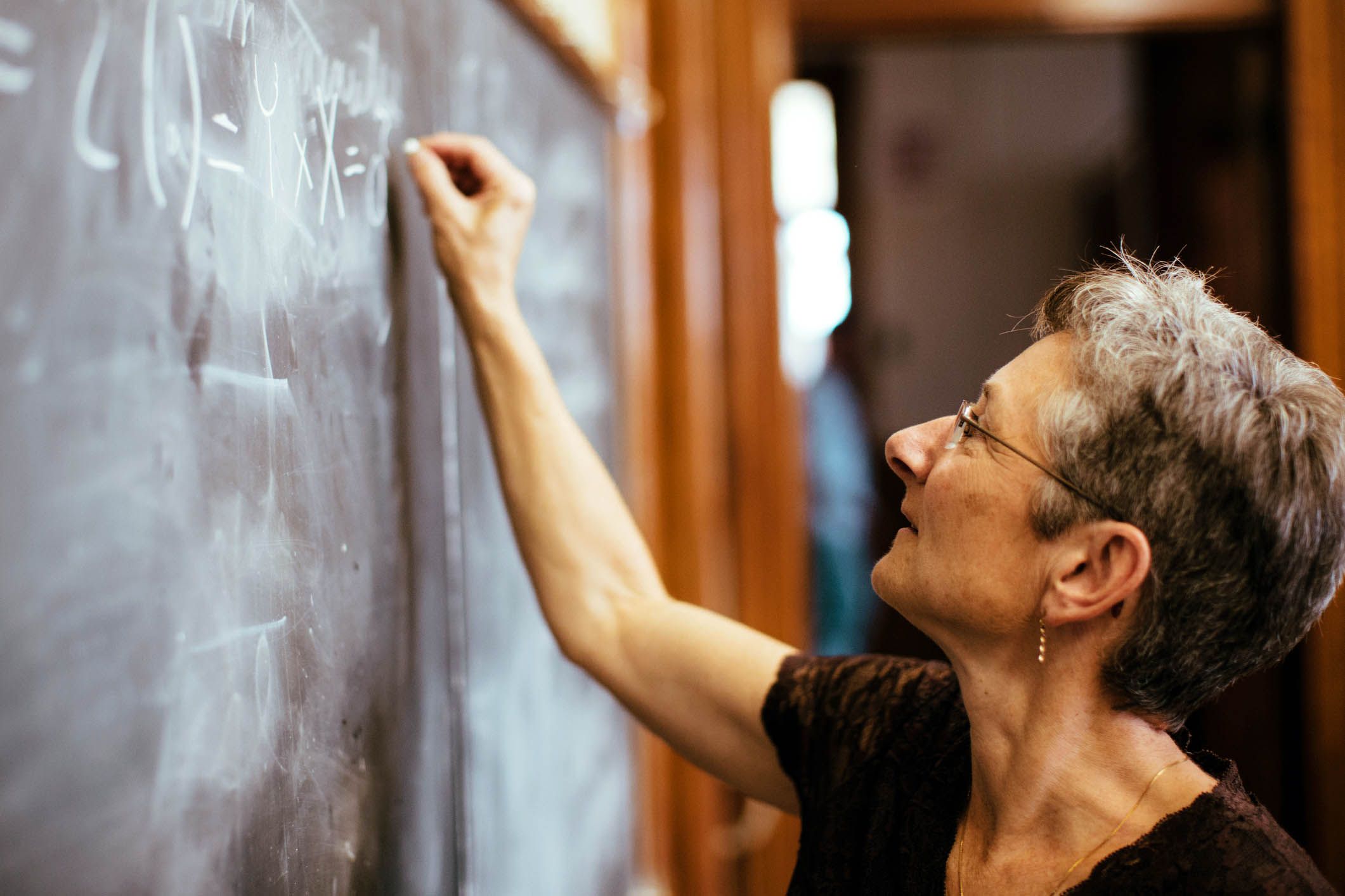 mathematics professor writing on chalkboard