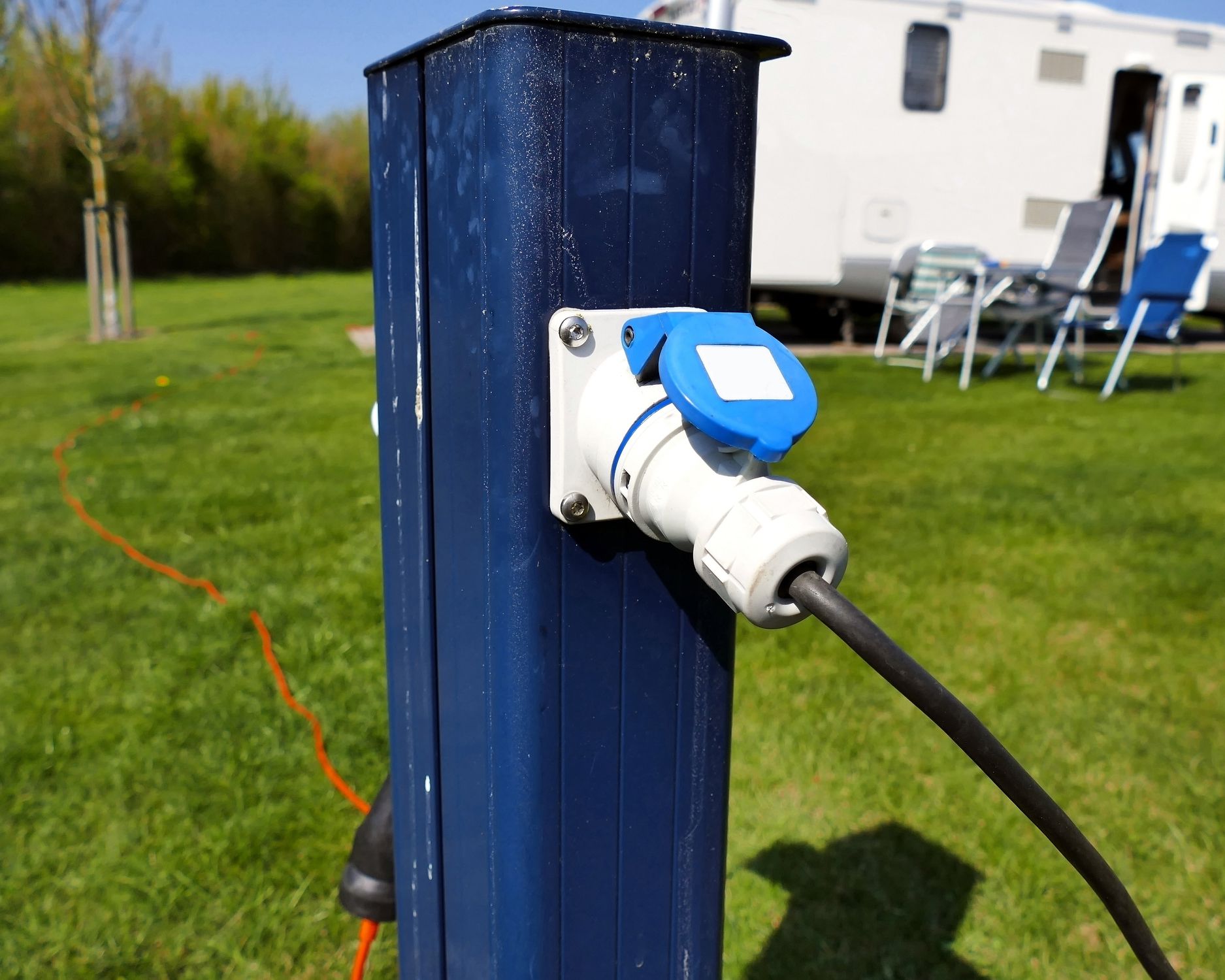 ac power sockets at camping site, plugged in, rv in background