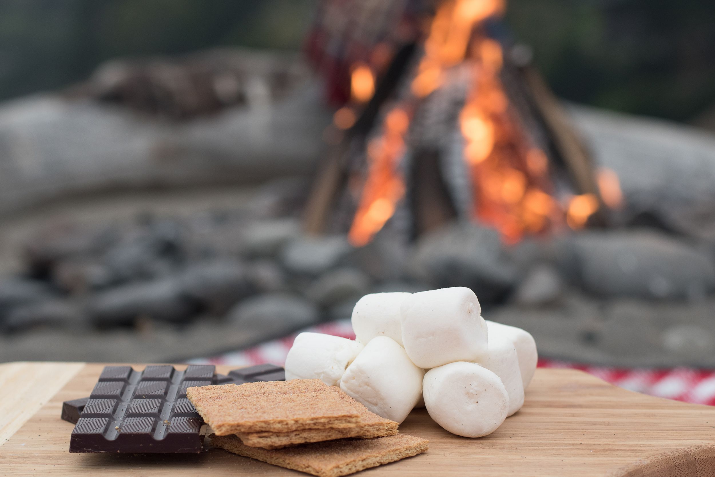 smores ingredients at a beach bonfire with chocolate, marshmellow, and graham crackers
