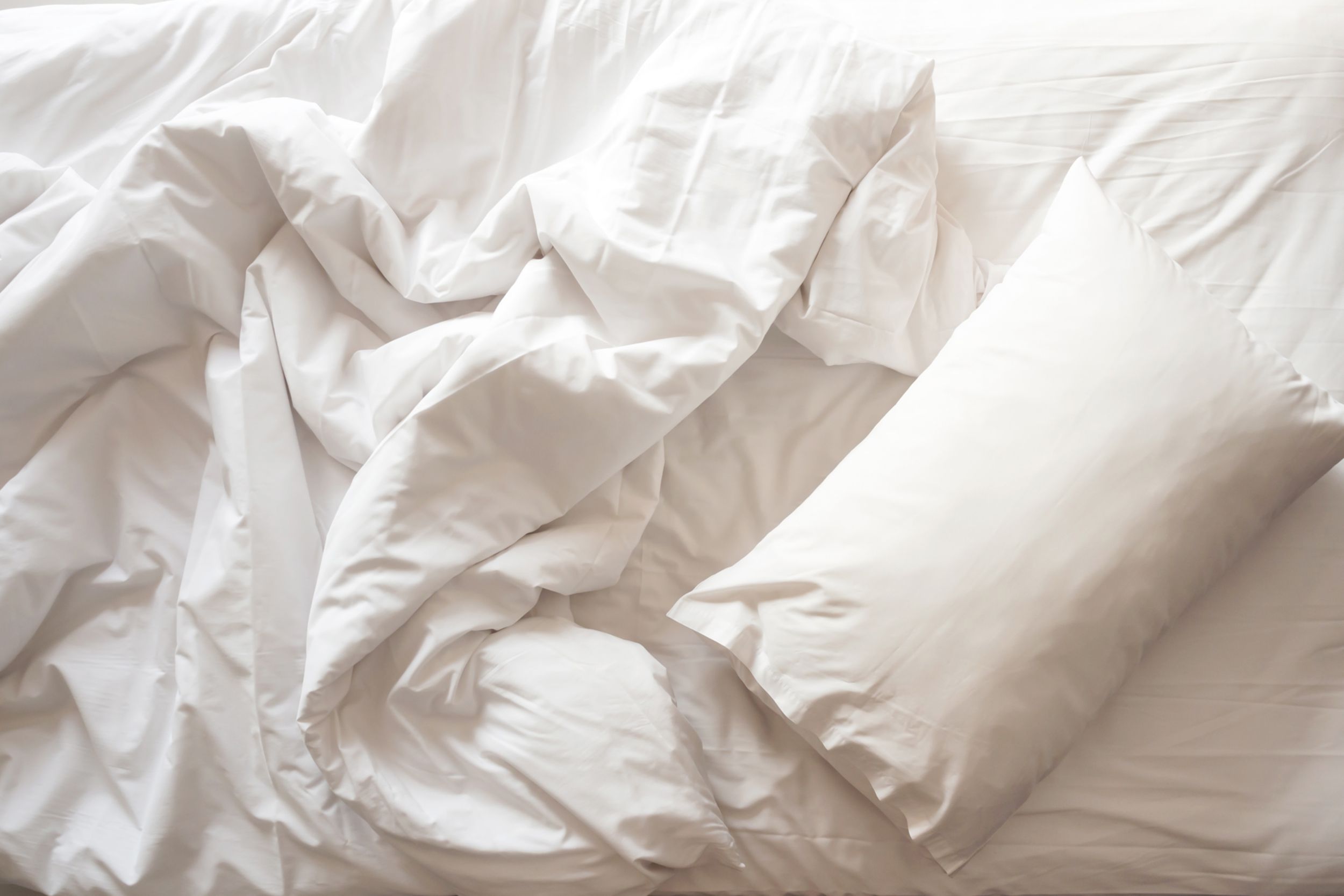 white pillow with blanket on bed unmade