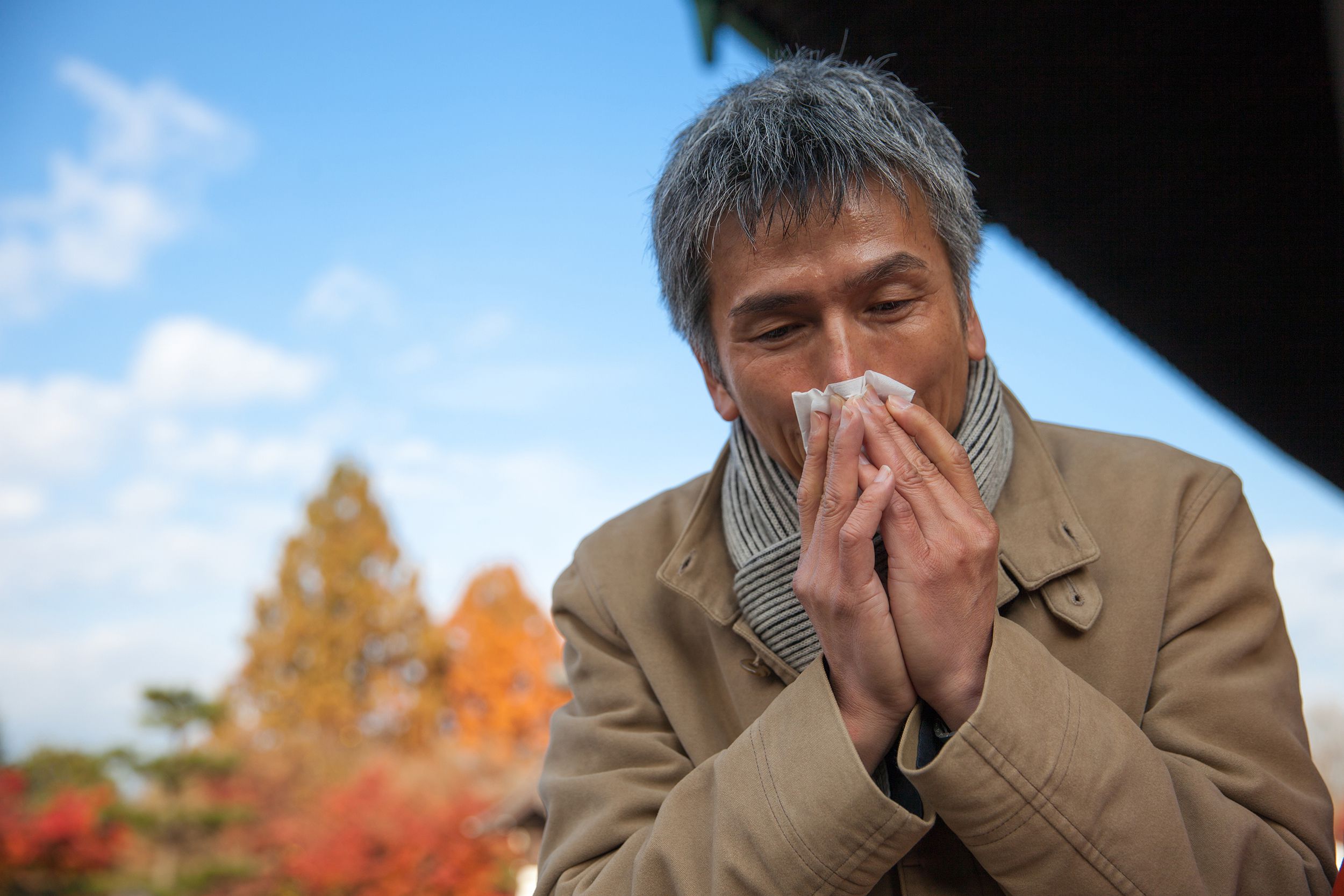 man outside sneezing during fall