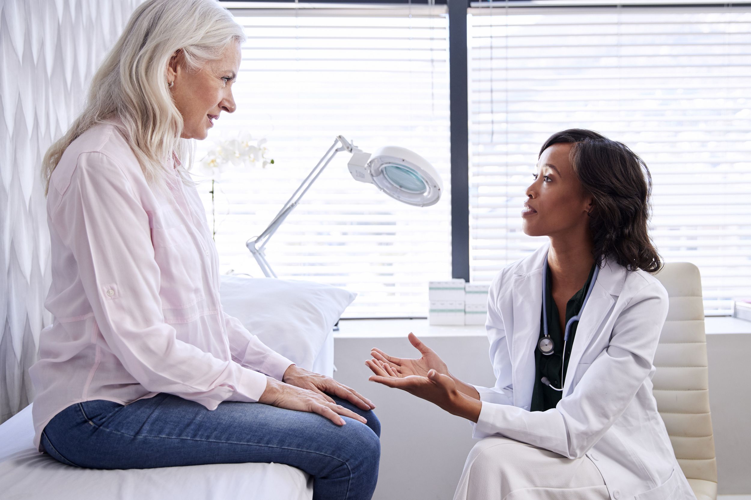 mature woman in consultation with female doctor sitting on examination couch in office