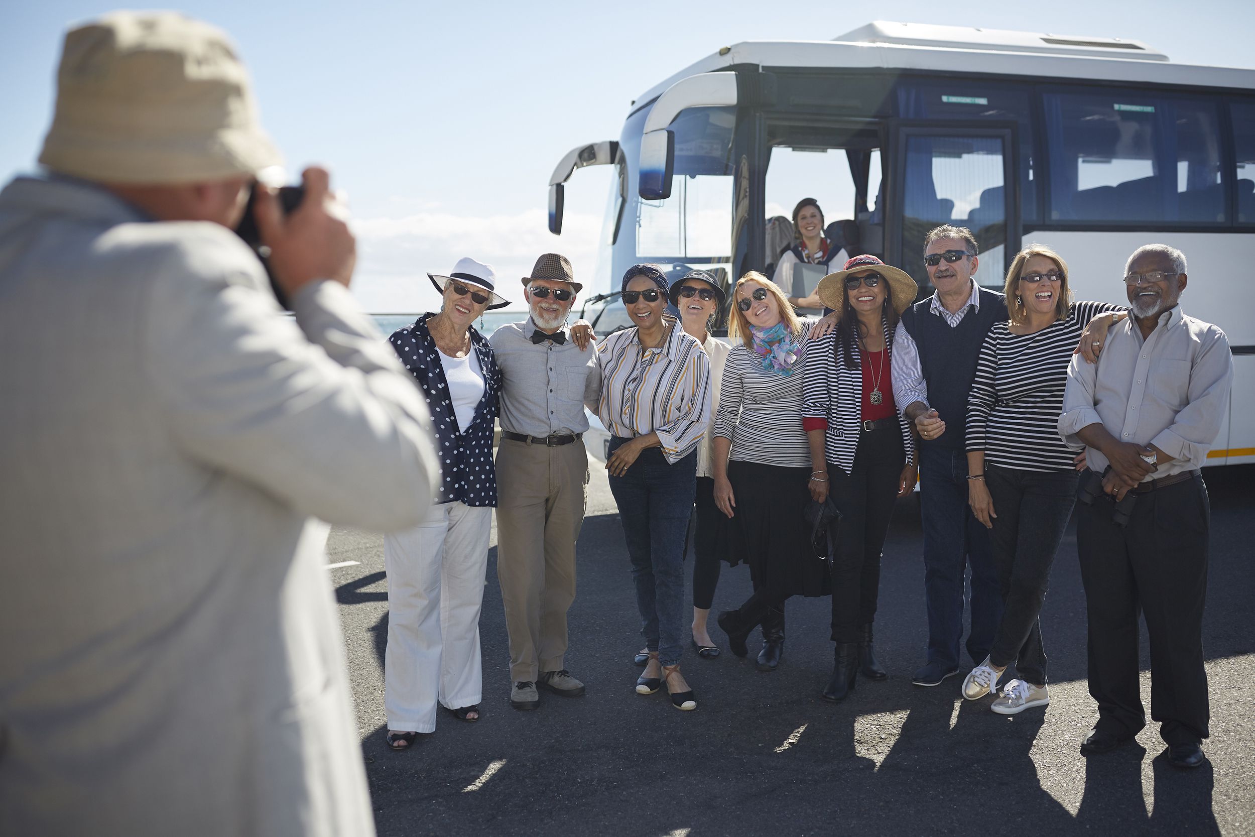 senior tourists posing outside bus