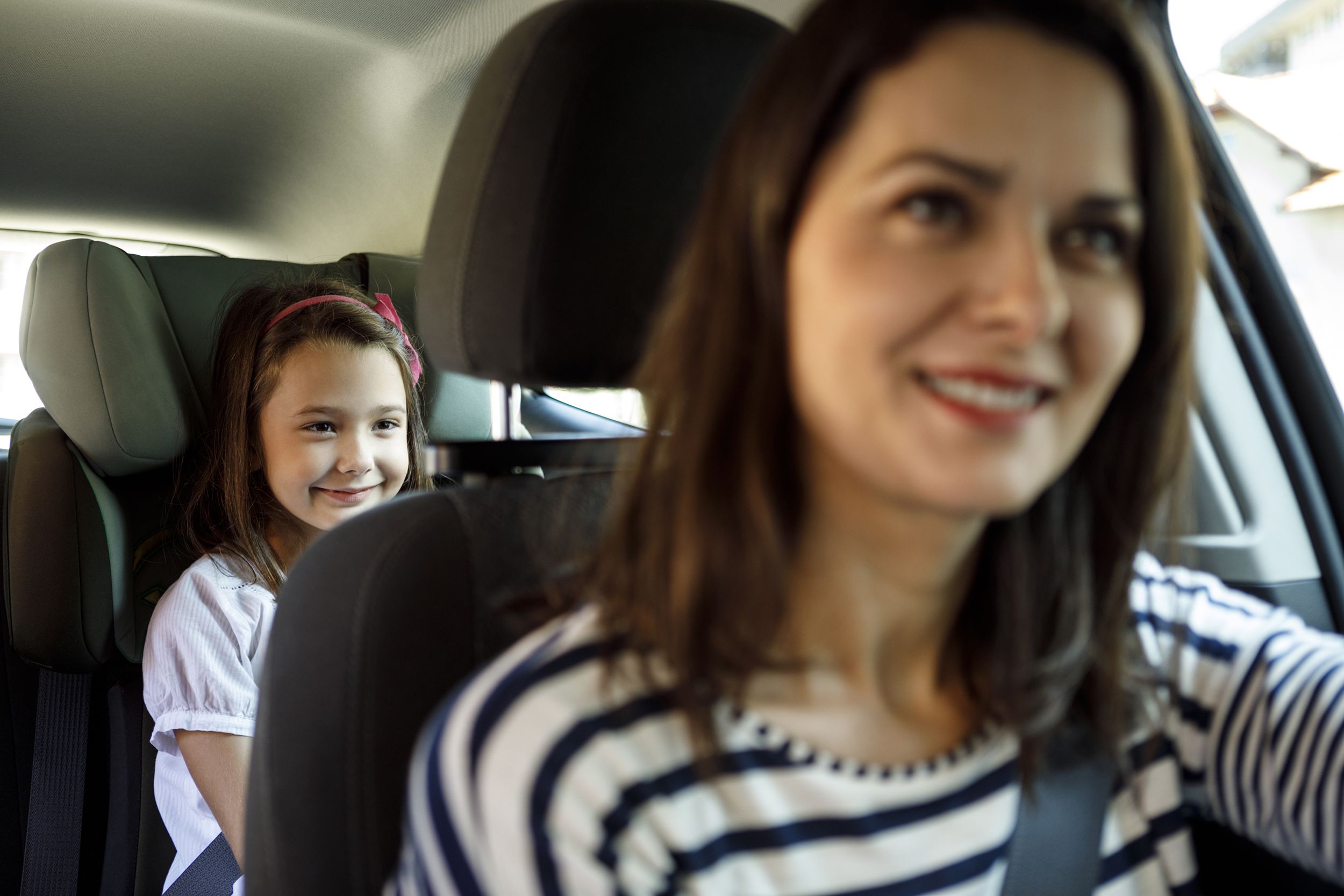 mother and little daughter driving in car together