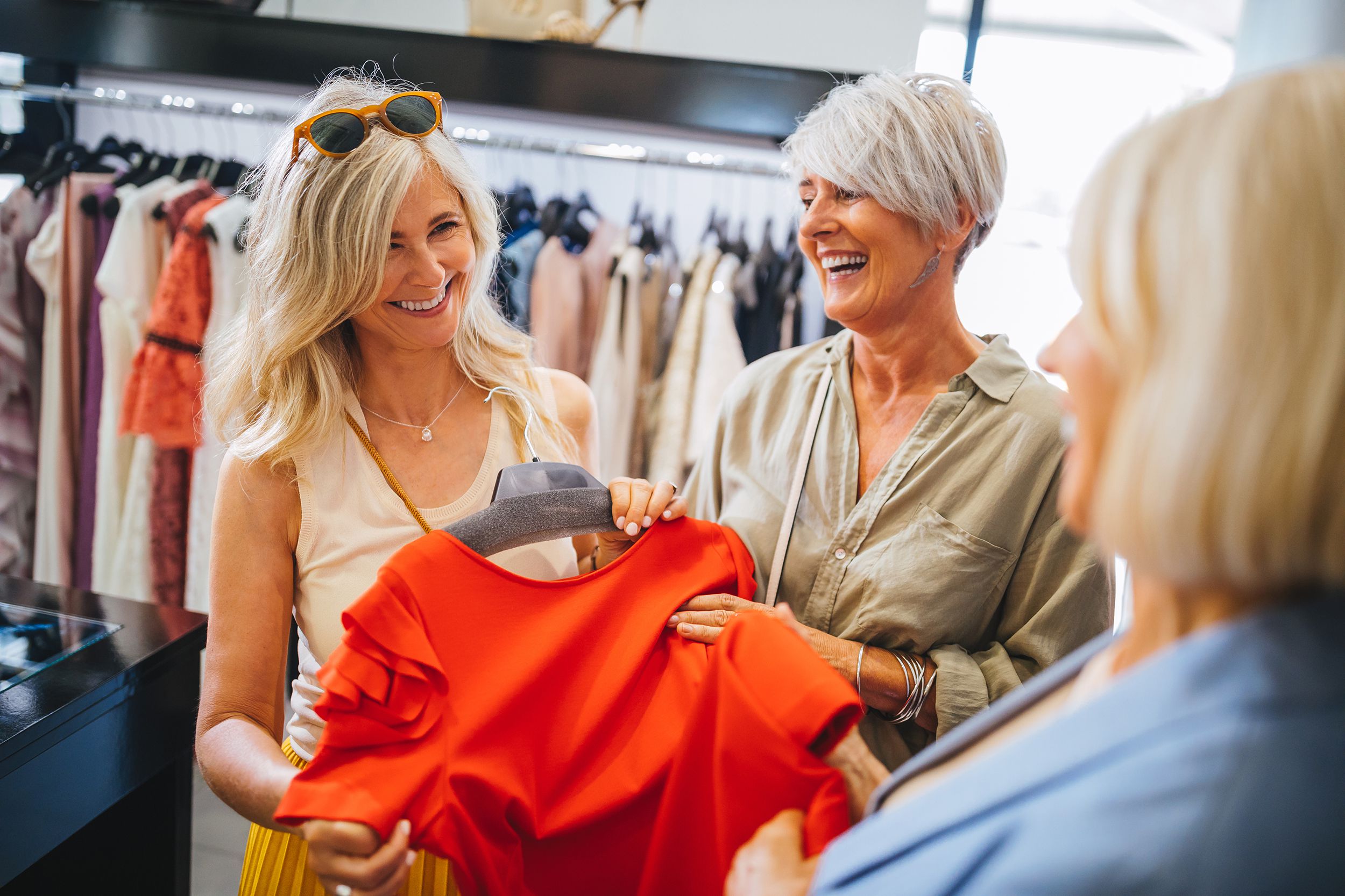 fashionable mature women shopping for clothes in fashion boutique
