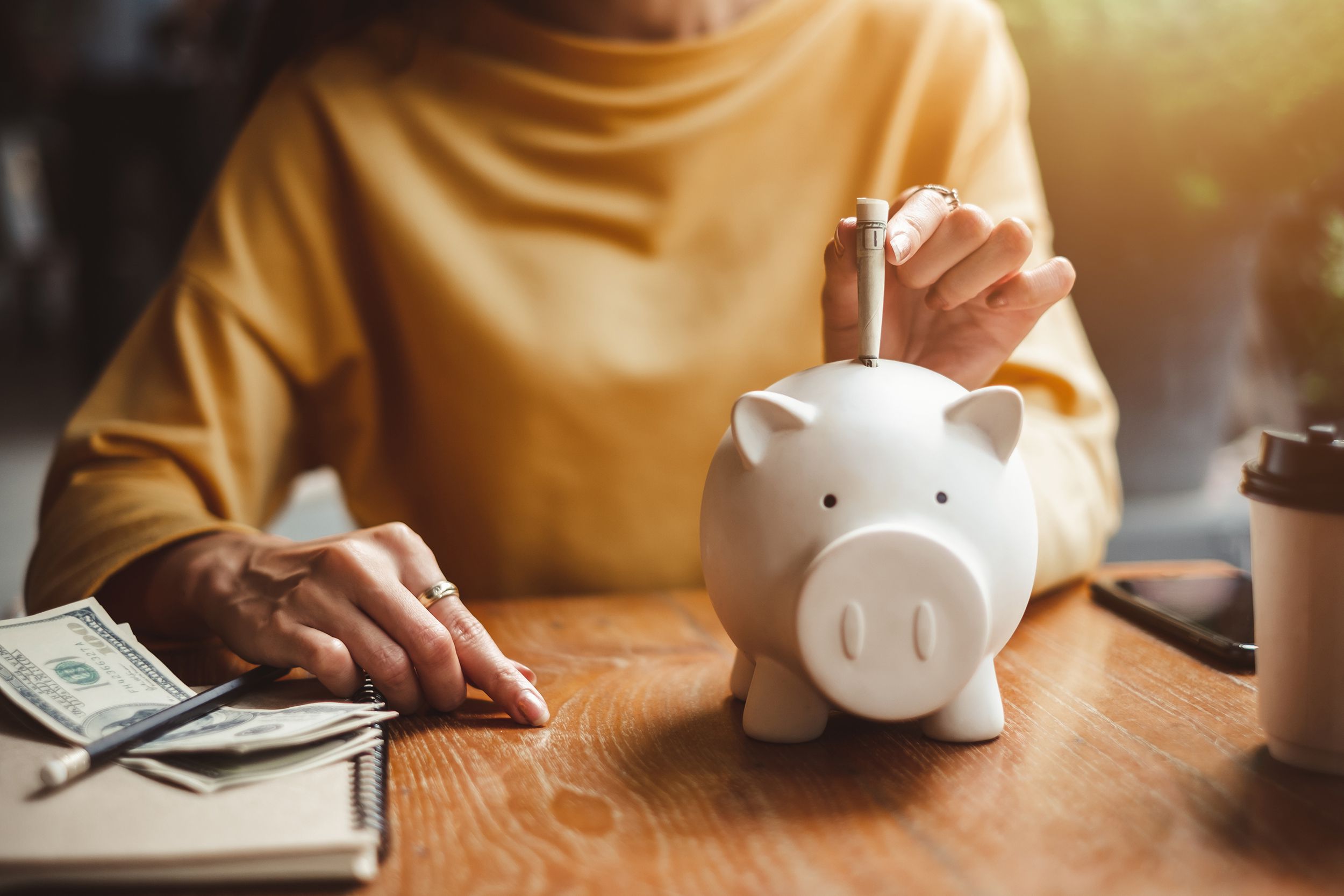 woman hand putting money bank note dollar into piggy bank