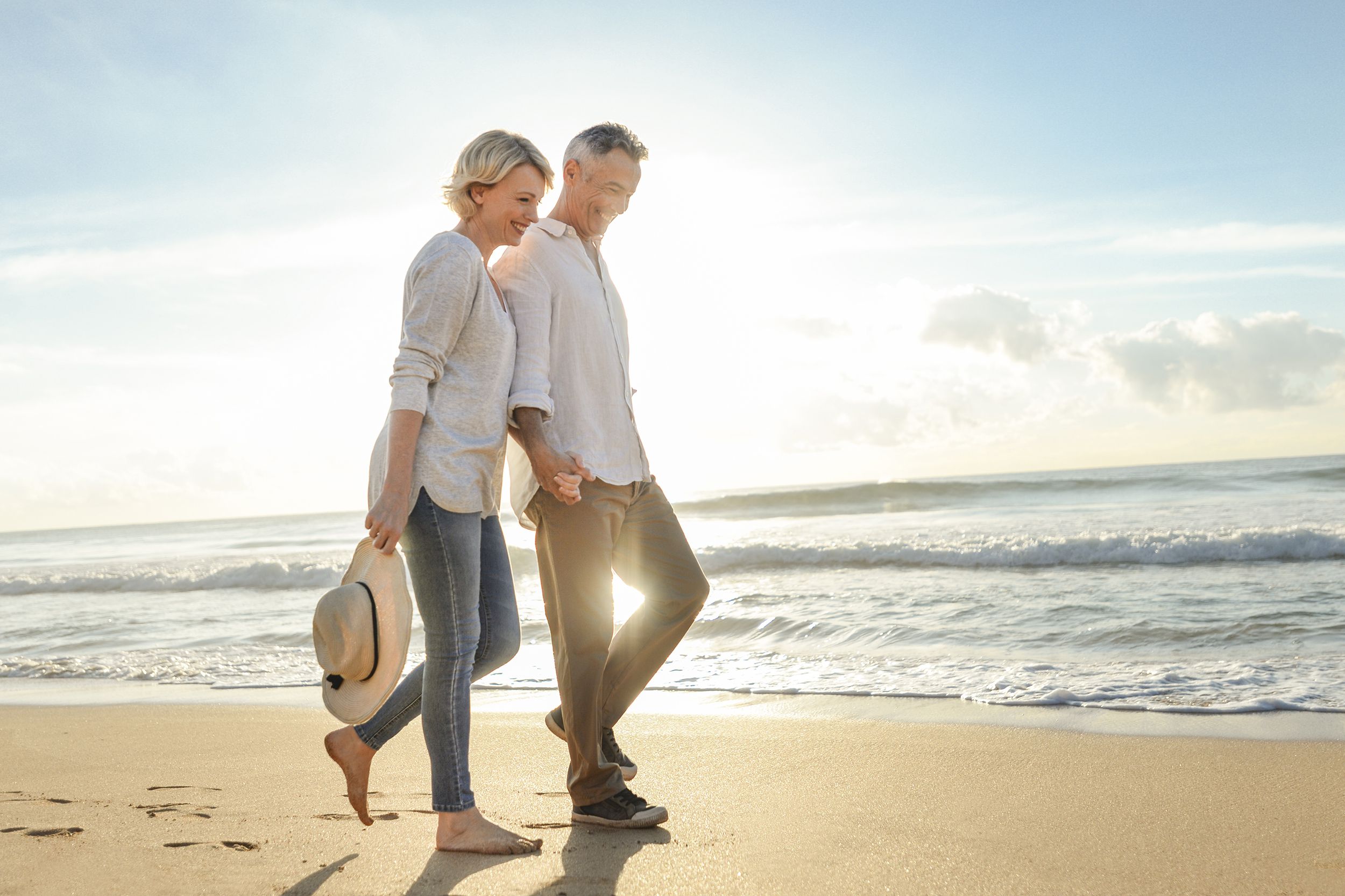 mature couple walking on the beach at sunset or sunrise
