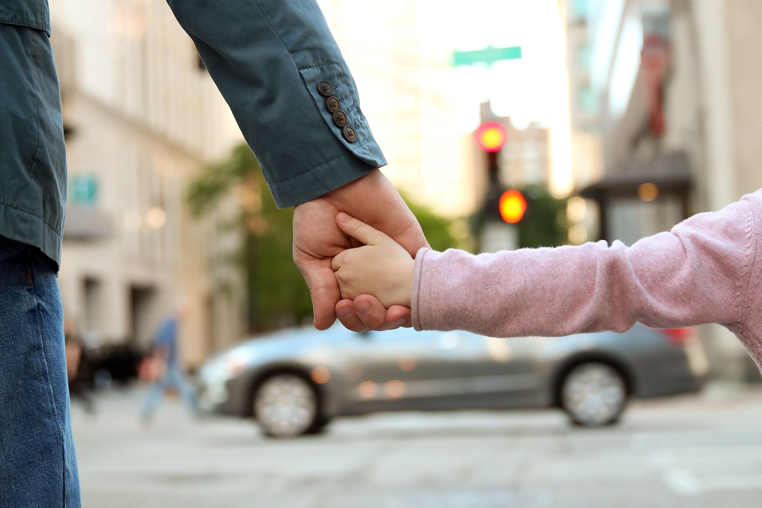 father holding the daughter/ child hand behind the traffic lights