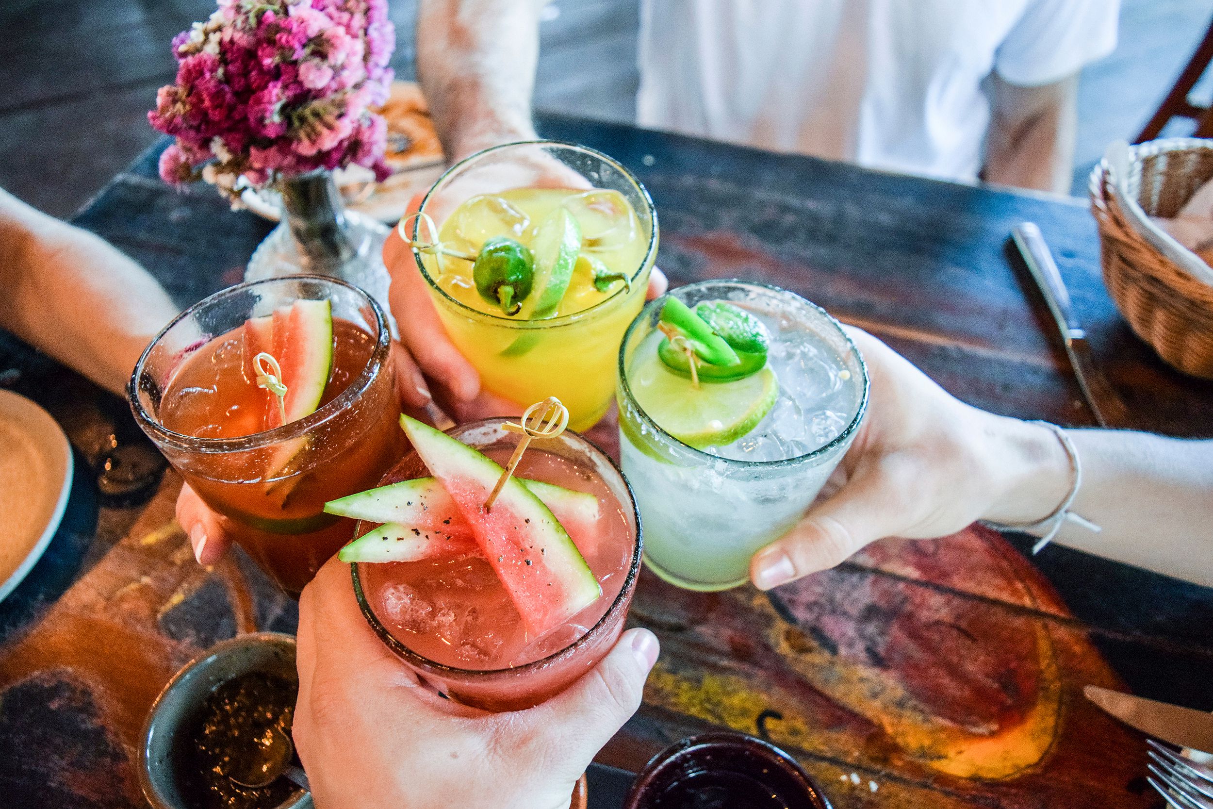 people toasting fruity cocktails at a table