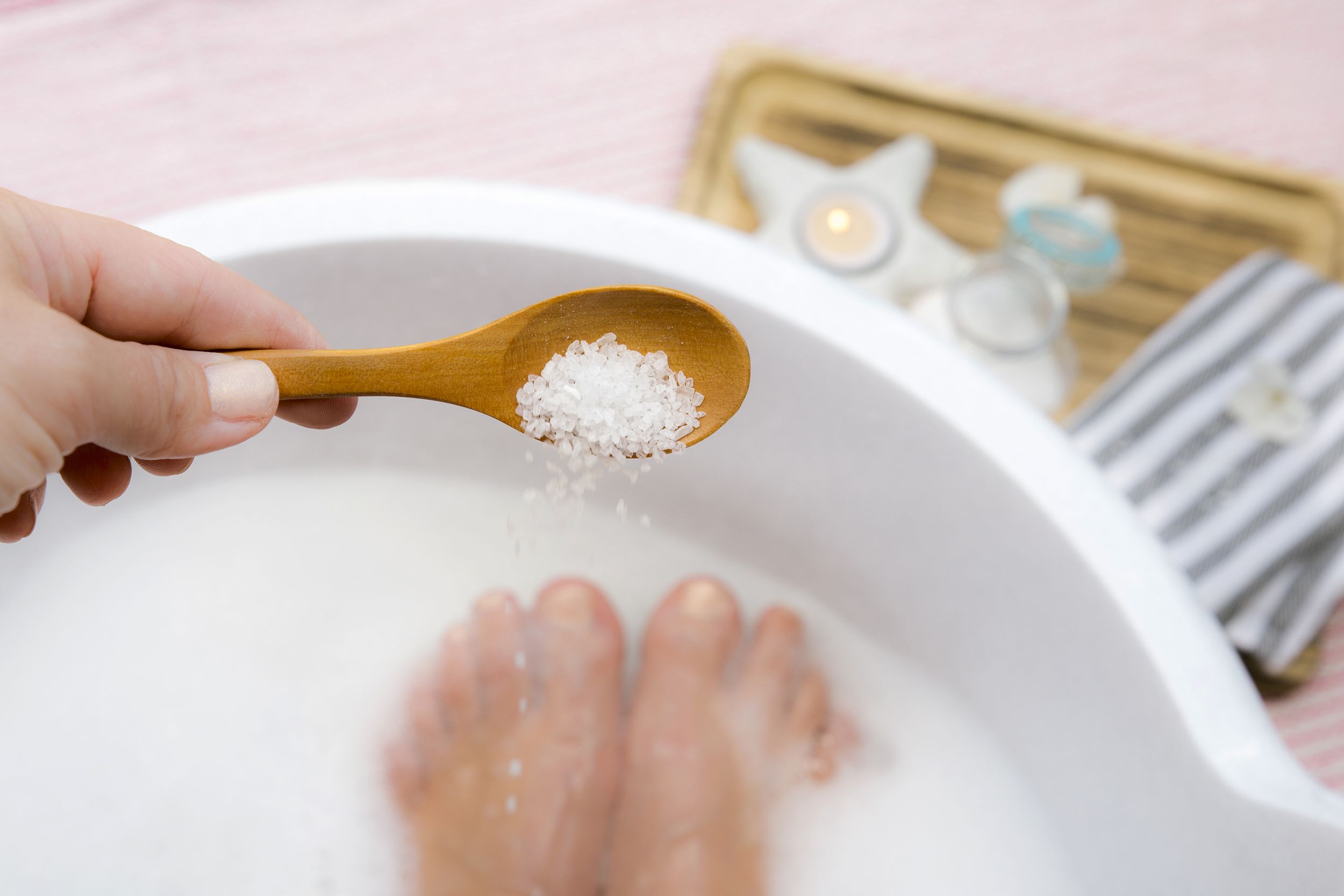 epsom salt being poured in bathtub while someone taking a bath