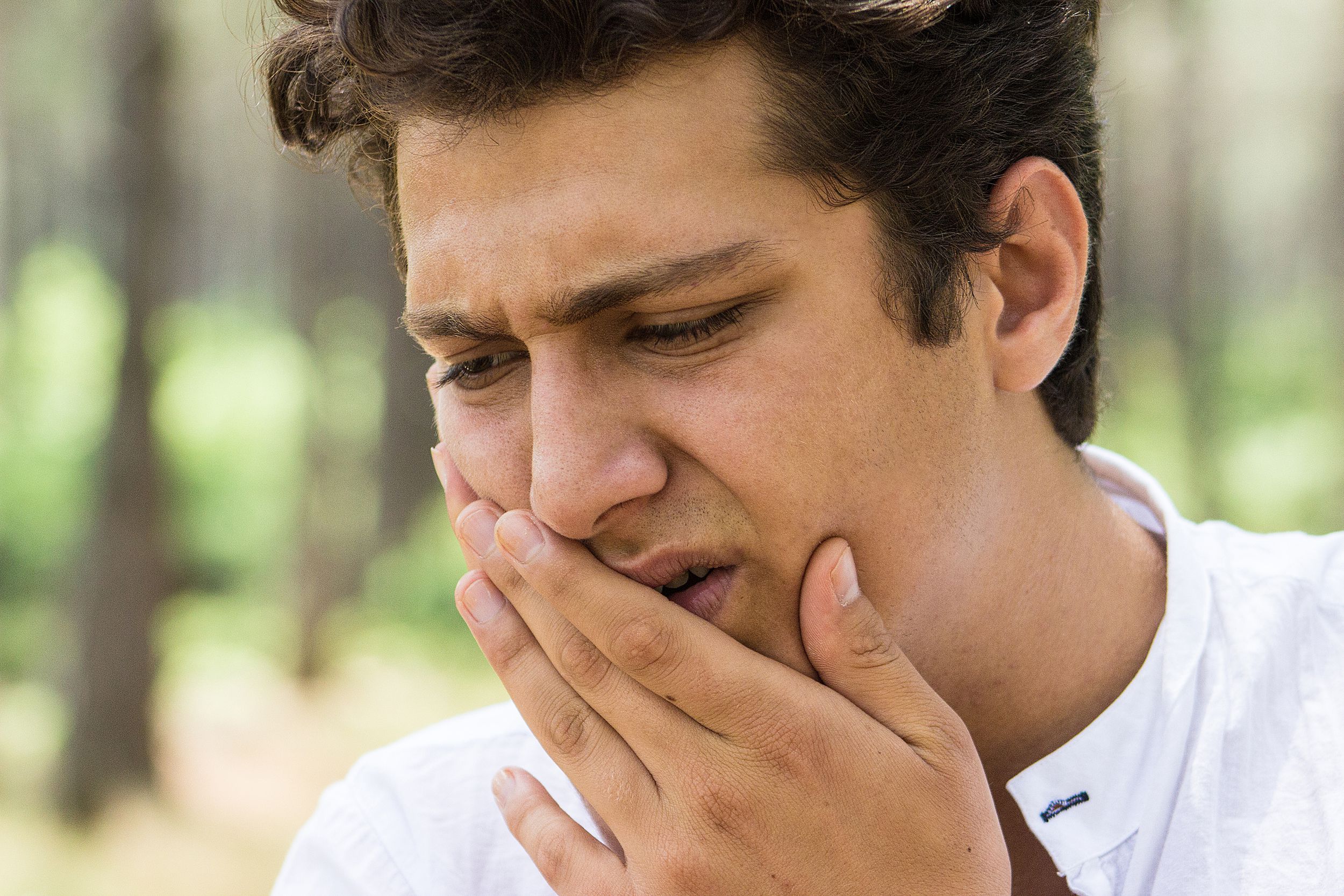 man feeling toothache and holding his jaw