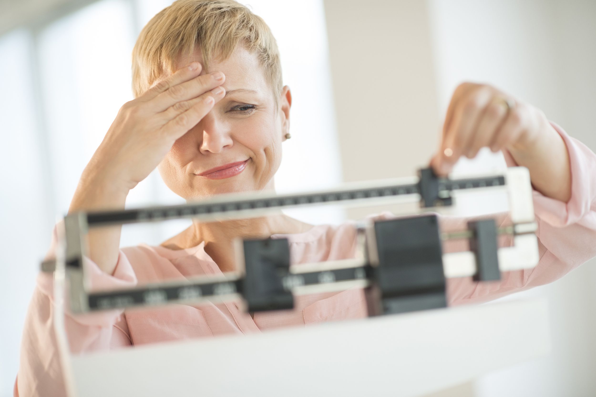 doubtful woman adjusting weight scale