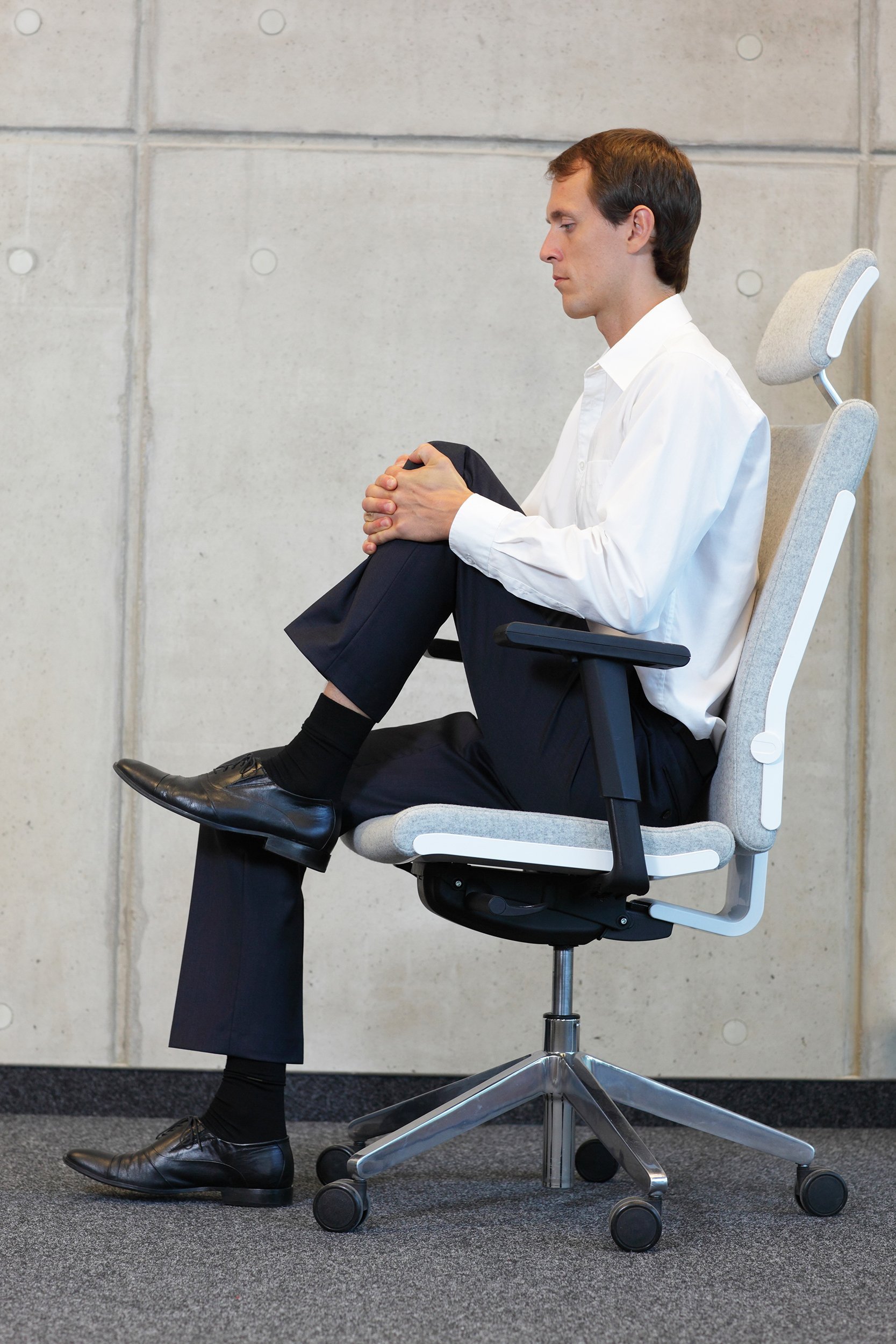 business man stretching his knees while in chair in office