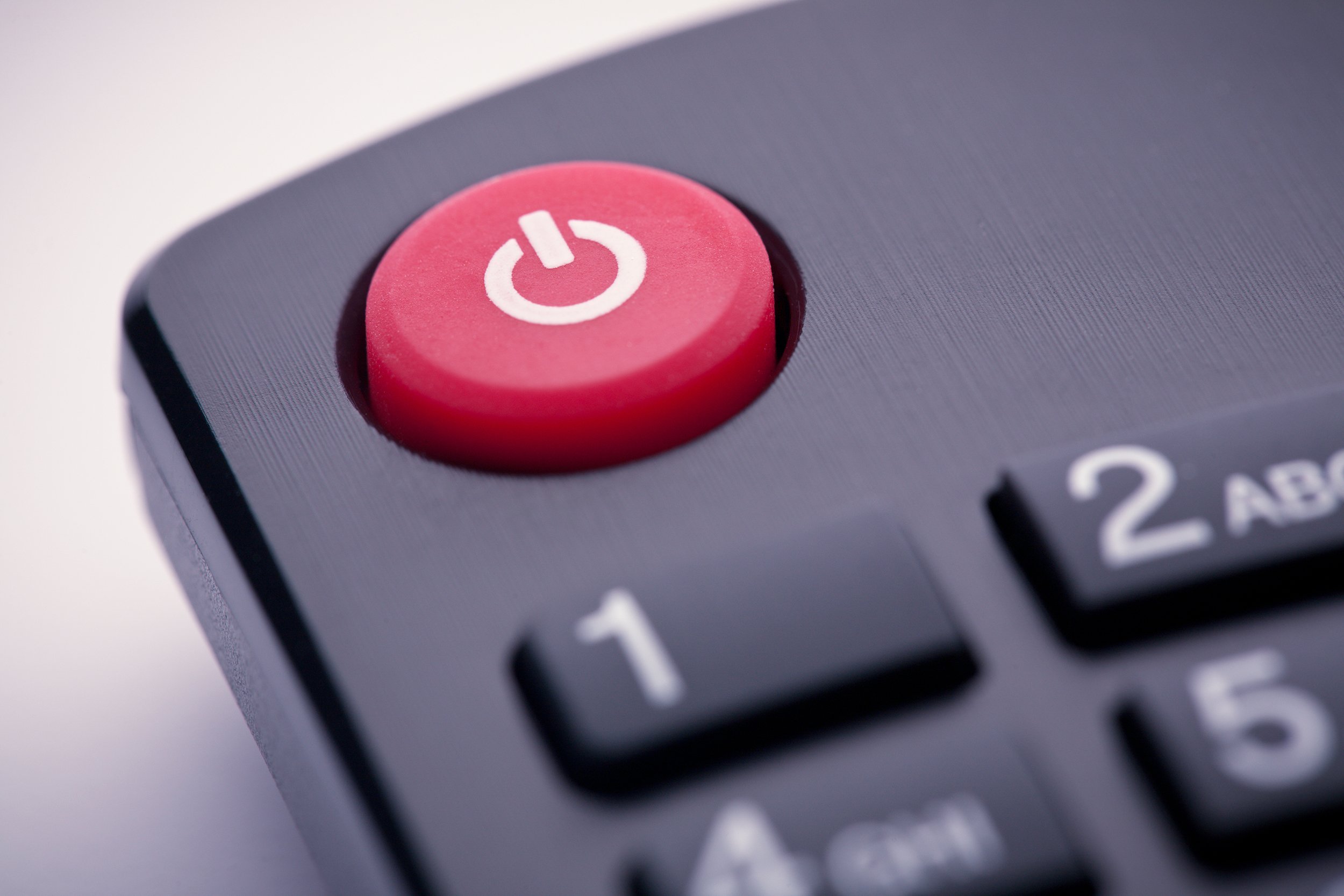 closeup image of a red power button on a remote control for a TV