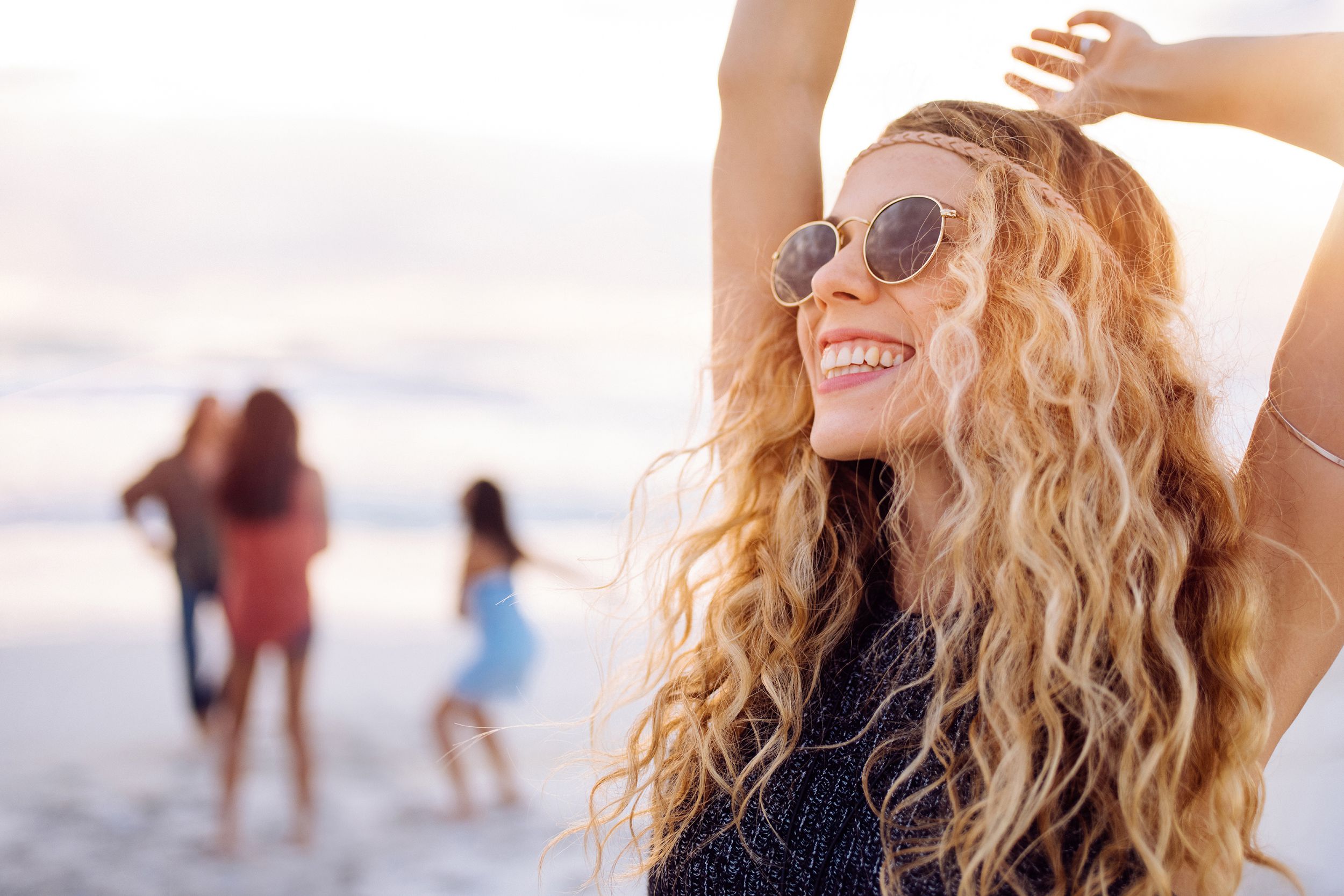 boho girl Dancing on beach with friends at seaside