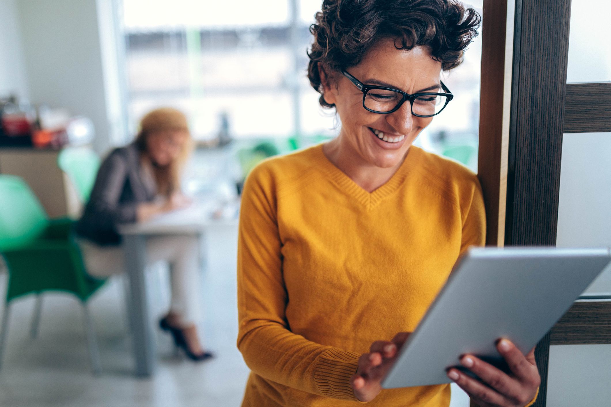 middle-aged woman at office smiling looking at tablet
