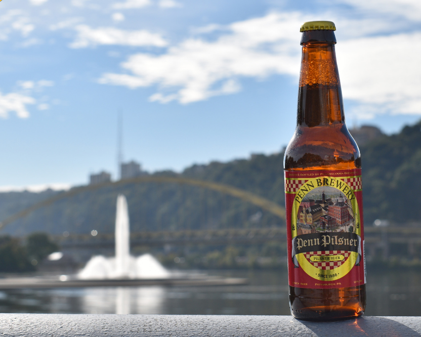 penn pilsner sitting in front of bridge in pittshburgh