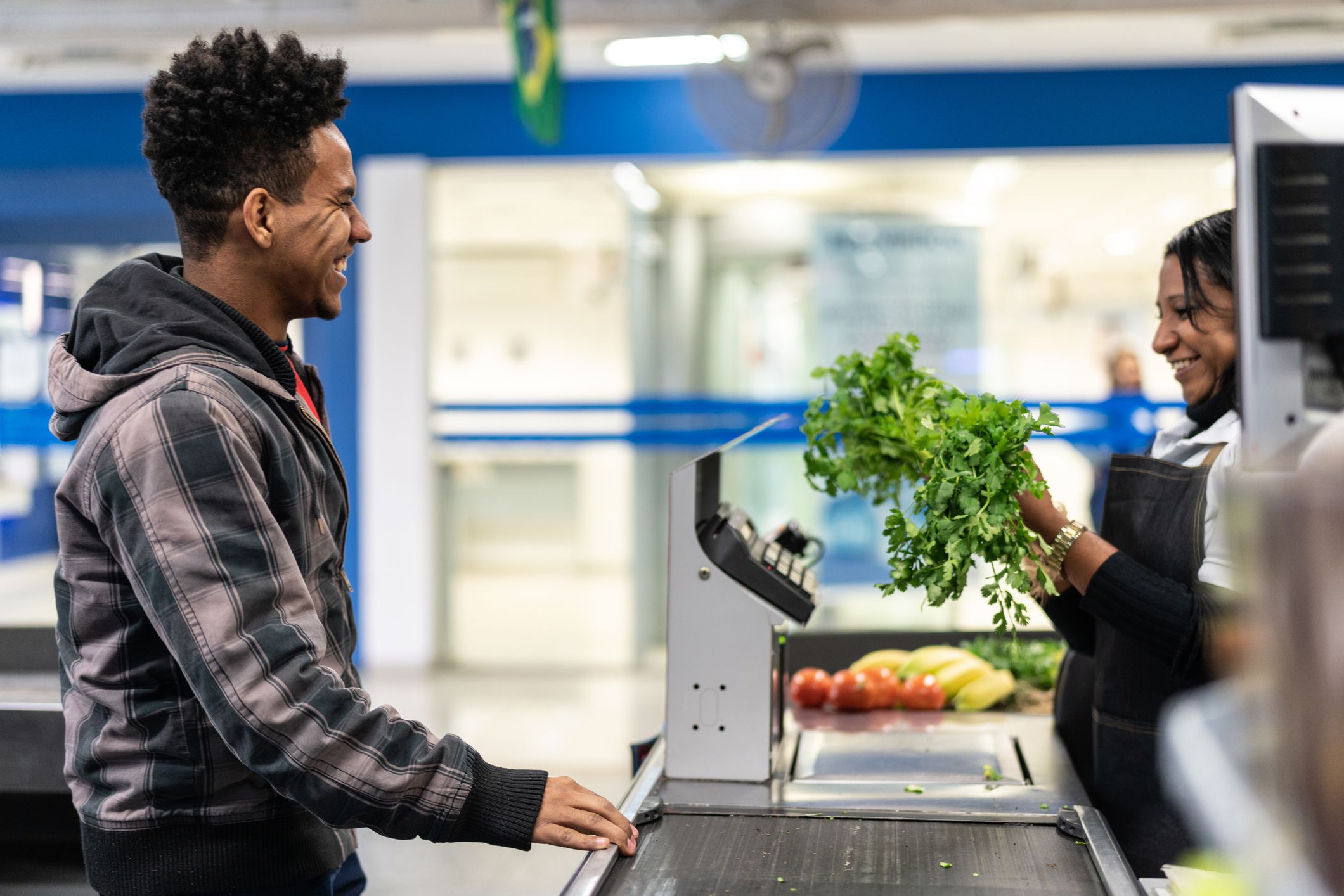 man smiling as grocery clerk rings up his products