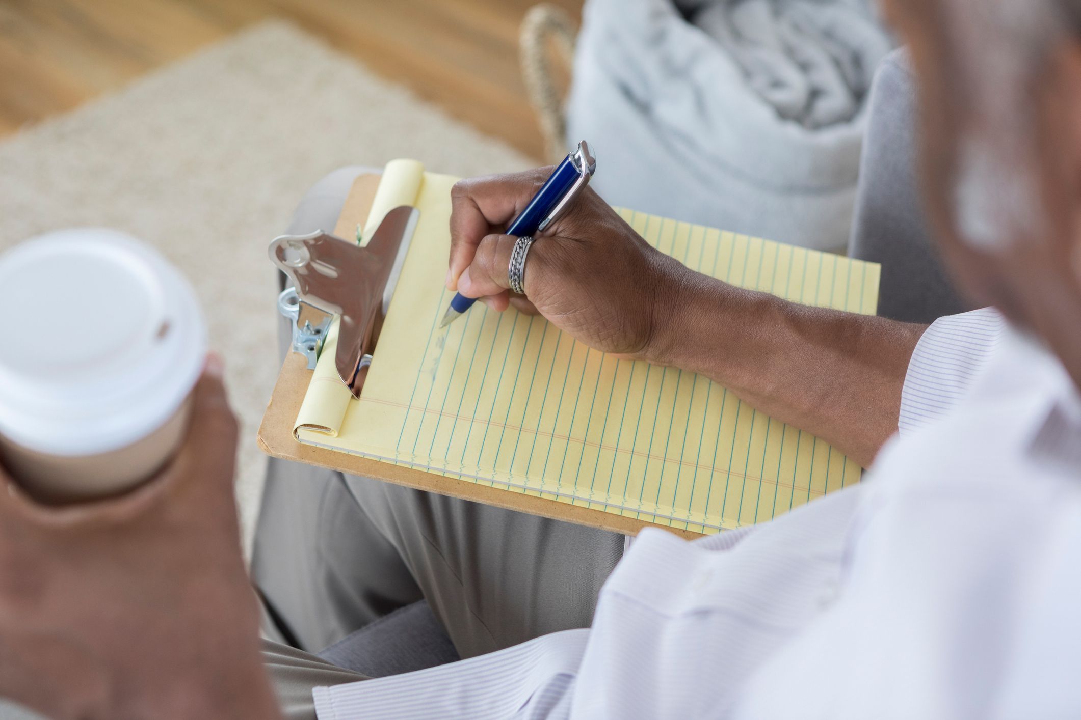 man writing notes on notepad