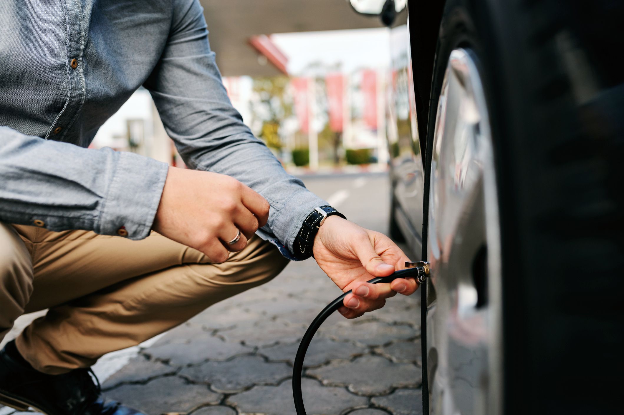 close-up of driver crouched inflating car tire