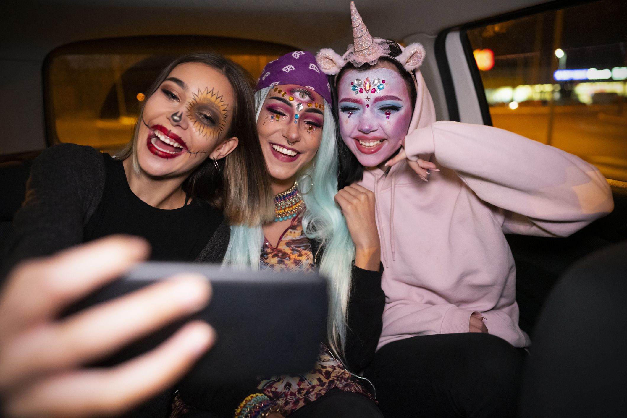 young women in costume taking selfie in backseat of car